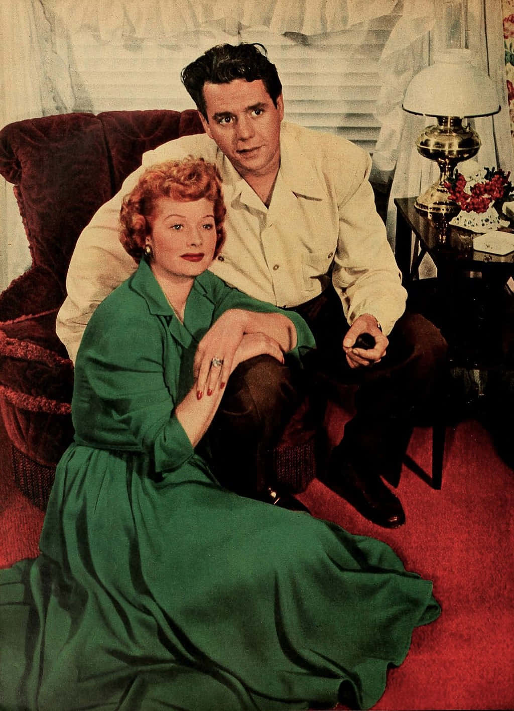 i love lucy 桌布 壁紙 — 一張復古照片，一男一女在溫暖照明的客廳中，一起在紅色地毯沙發上擺姿勢。
