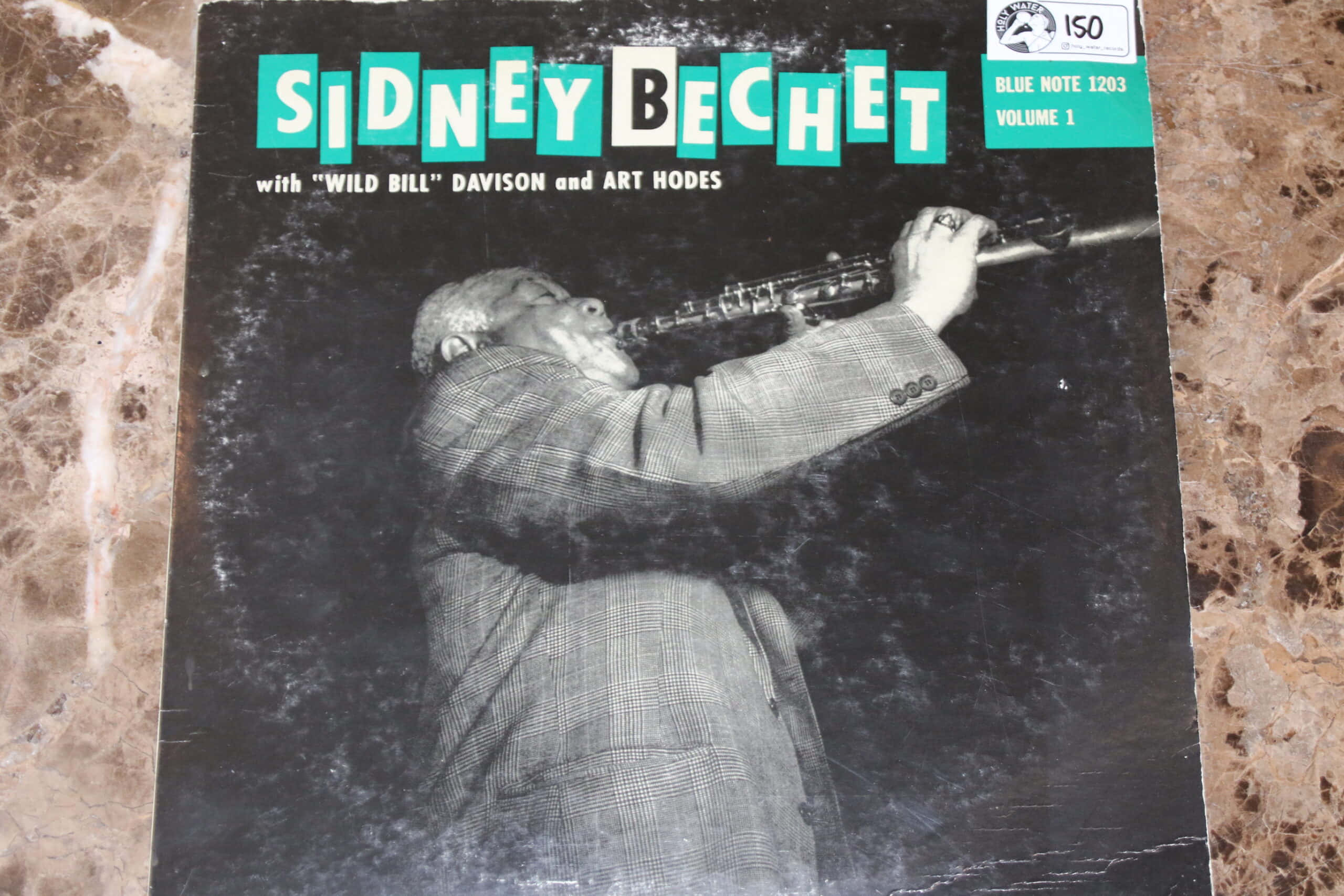 Album Cover 桌布 壁紙 — 一張復古爵士專輯封面顯示Sidney Bechet在深色紋理背景上熱情地演奏高音薩克斯風。