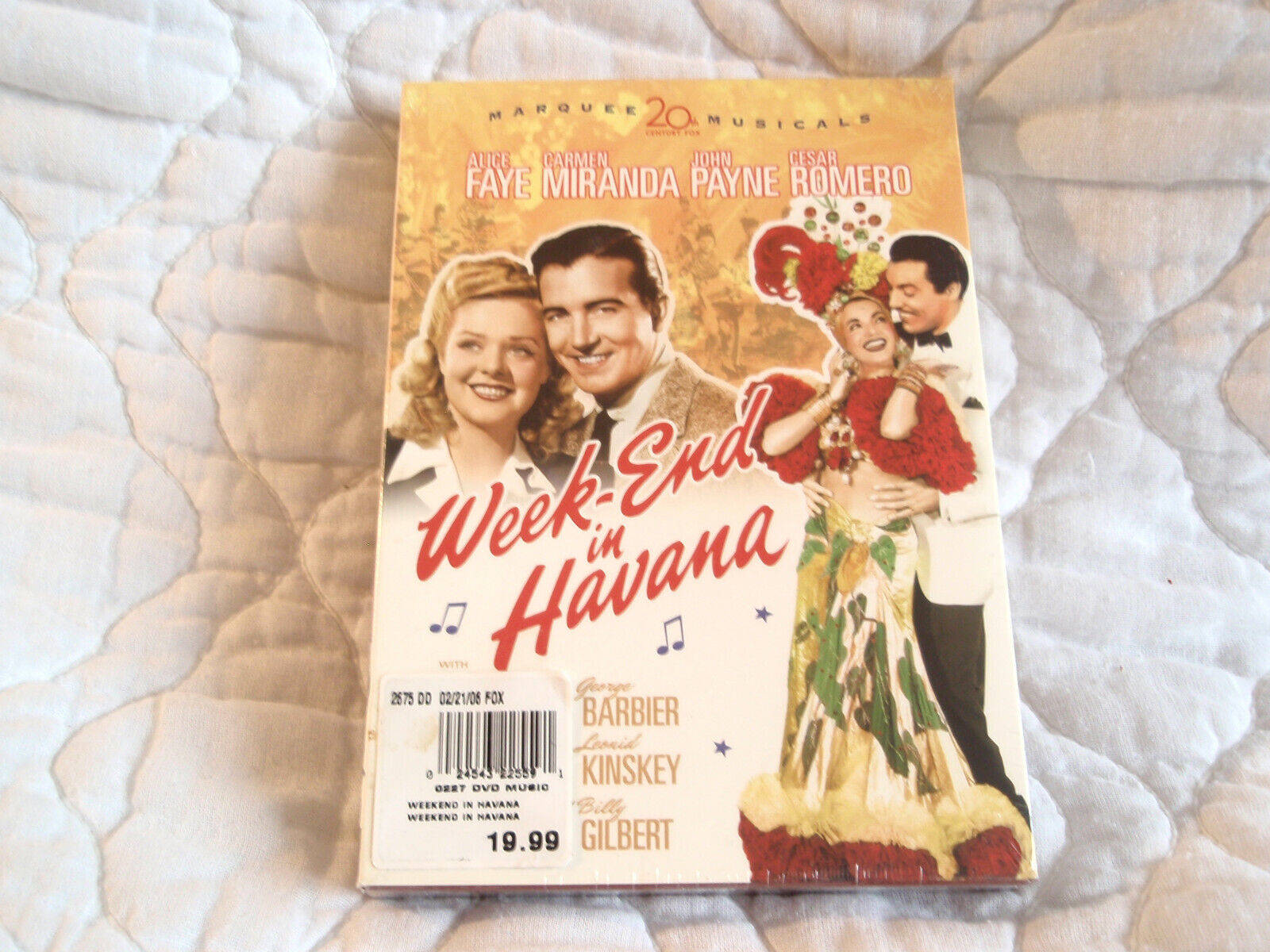 電影動圖 桌布 壁紙 — 一張復古的《Week End in Havana》DVD封面放在白色絎縫布料表面上。