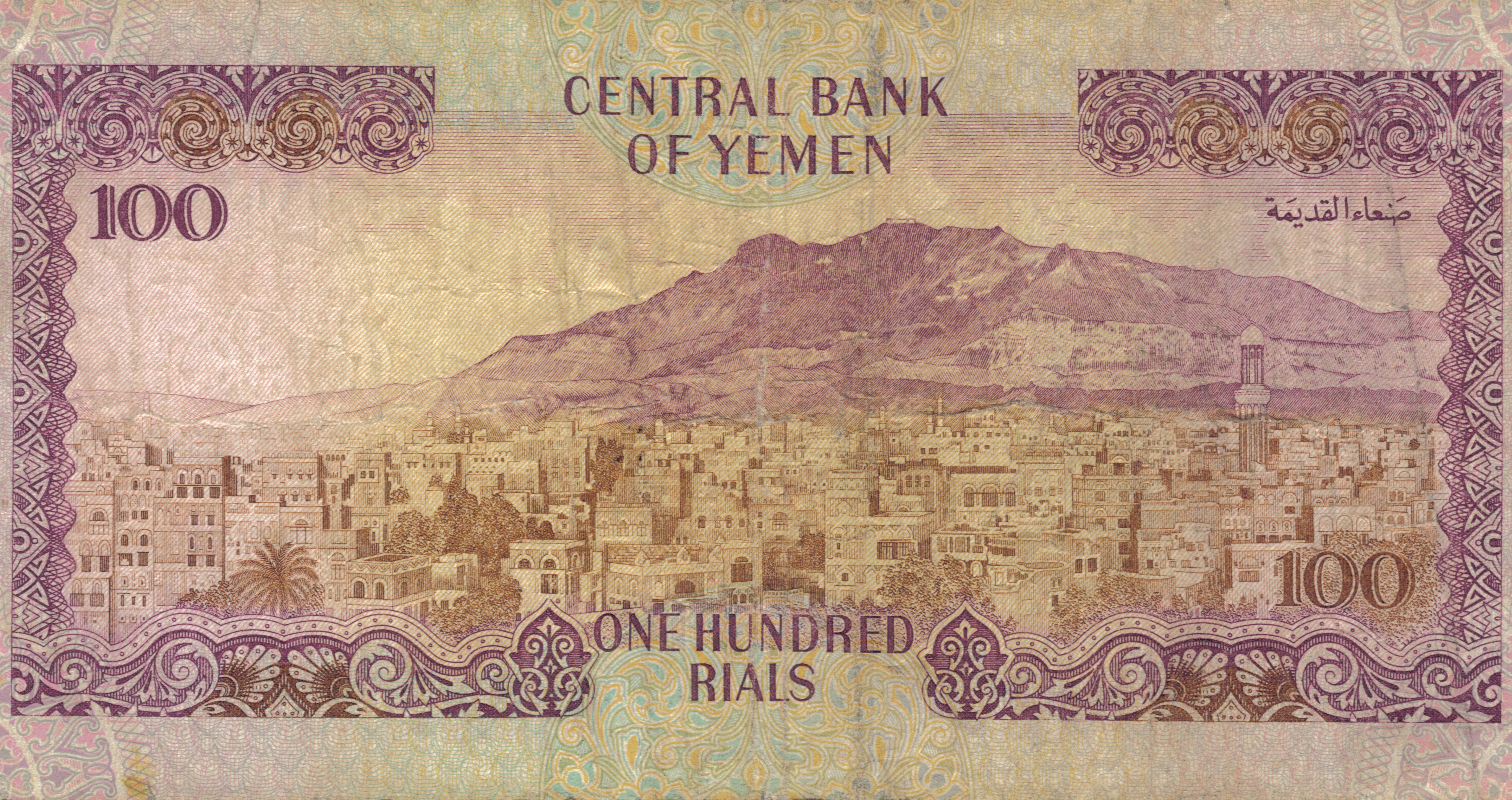 Yemen 桌布 壁紙 — 一張復古的100葉門里亞爾紙幣，上面有詳細的山城景觀插圖，帶有傳統建築和華麗的紫色邊框。