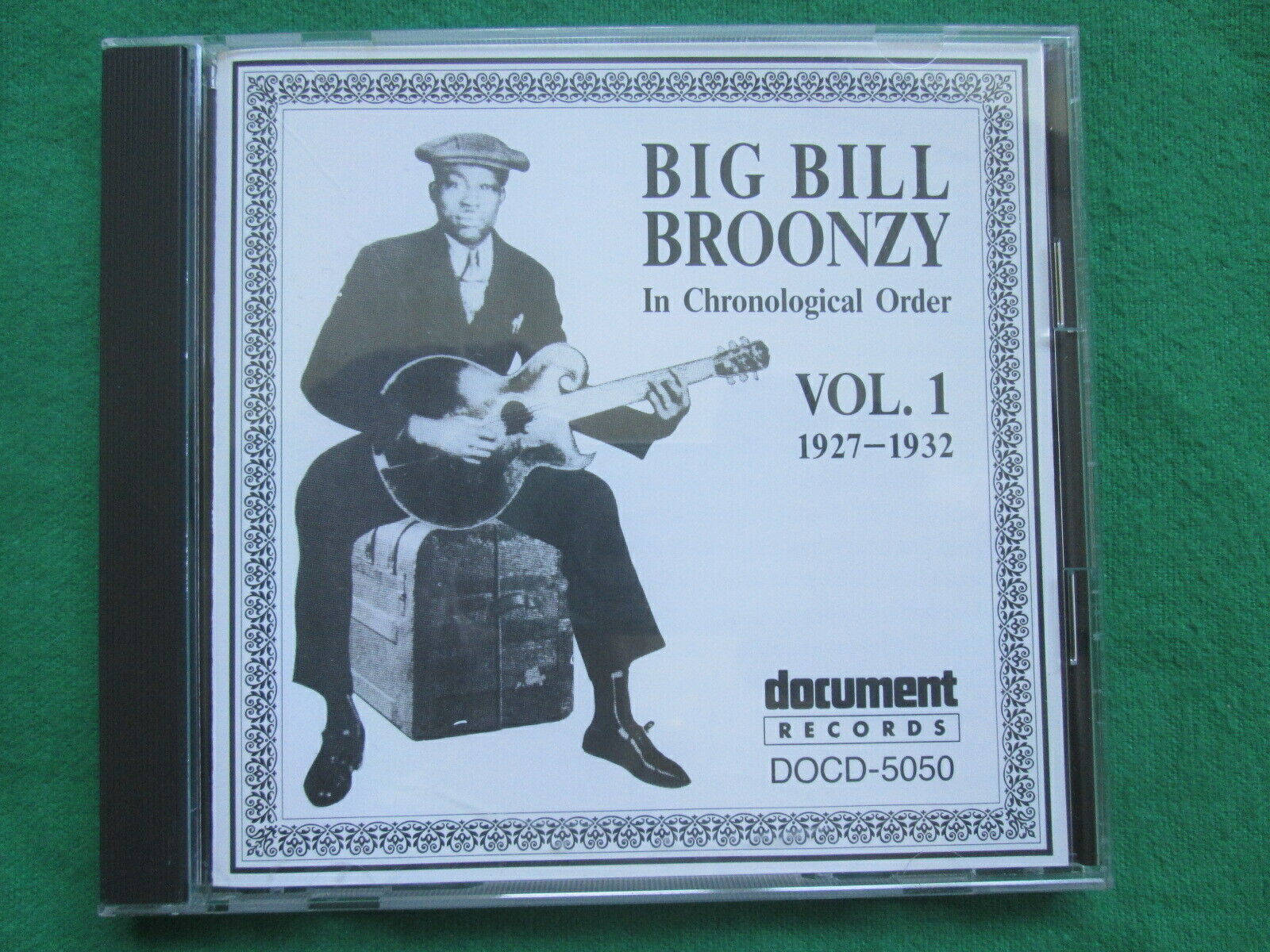 poster 桌布 壁紙 — 一張復古黑白CD封面，Big Bill Broonzy坐在行李箱上，手持吉他，背景為綠色布料。