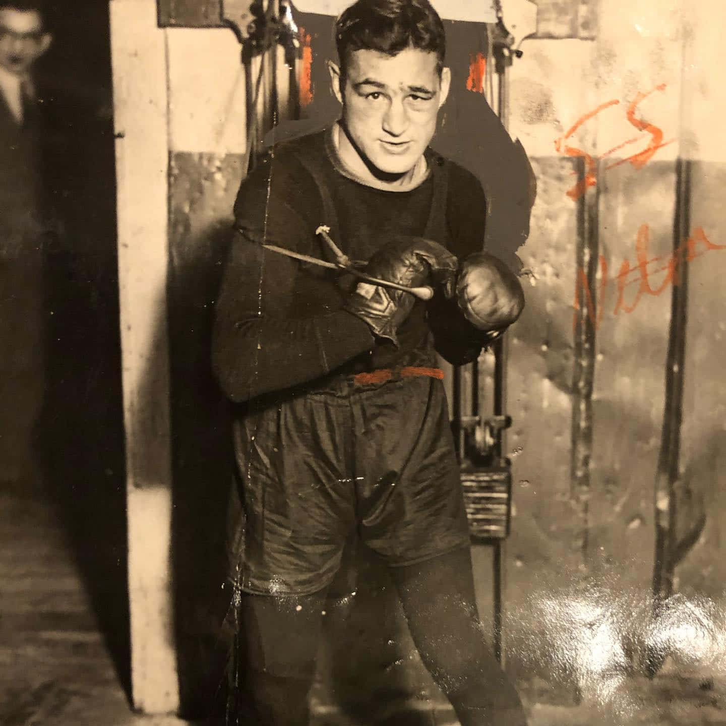 Boxing 桌布 壁紙 — 一張復古黑白照片，一名拳擊手穿著訓練裝備，在簡陋的健身房裡拿著一根棍子。
