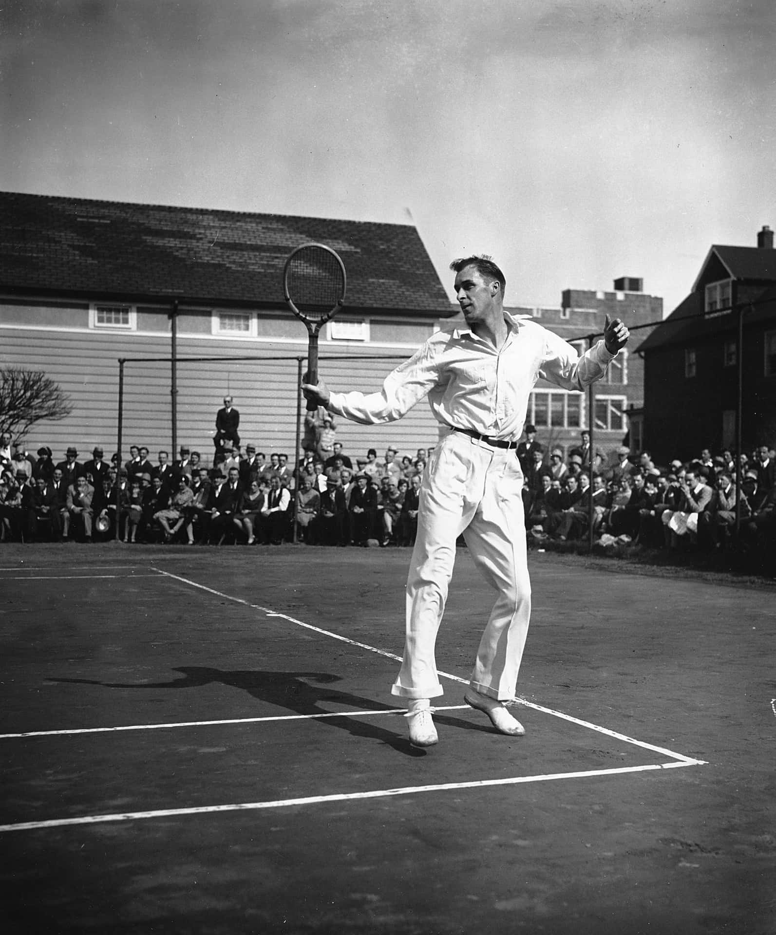Tennis 桌布 壁紙 — 一張復古黑白照片，一名男性網球運動員在戶外球場上揮拍，觀眾在旁觀看。