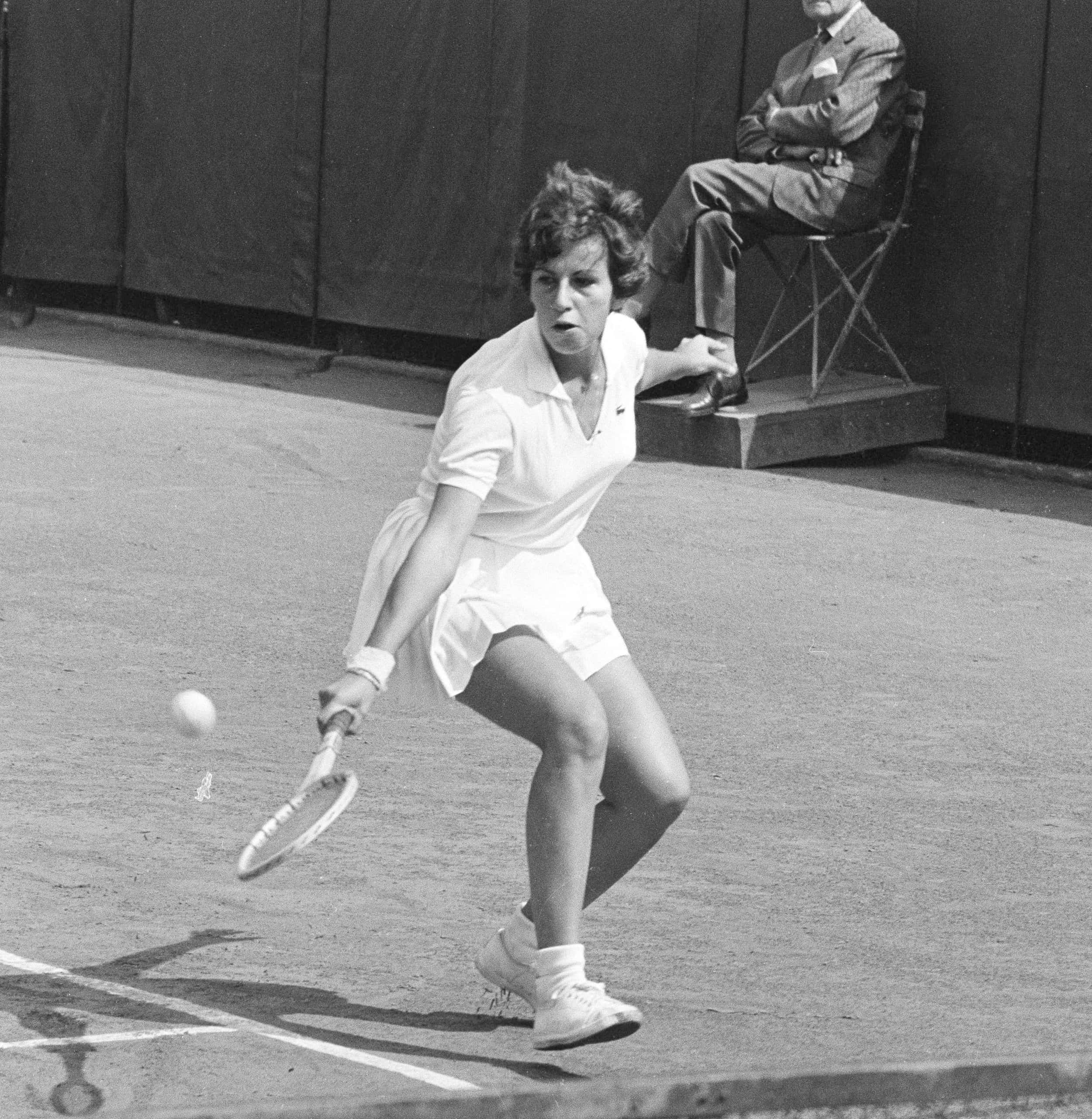 Tennis 桌布 壁紙 — 一張復古黑白照片，拍攝一位女網球選手在紅土球場上揮拍，背景有一位觀眾。