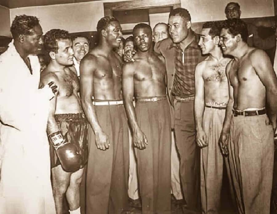 Boxing 桌布 壁紙 — 一張復古黑白照片，顯示一群赤裸上身的拳擊手和穿著西裝的男人聚集在一個有溫暖燈光和木鑲板的房間裡。