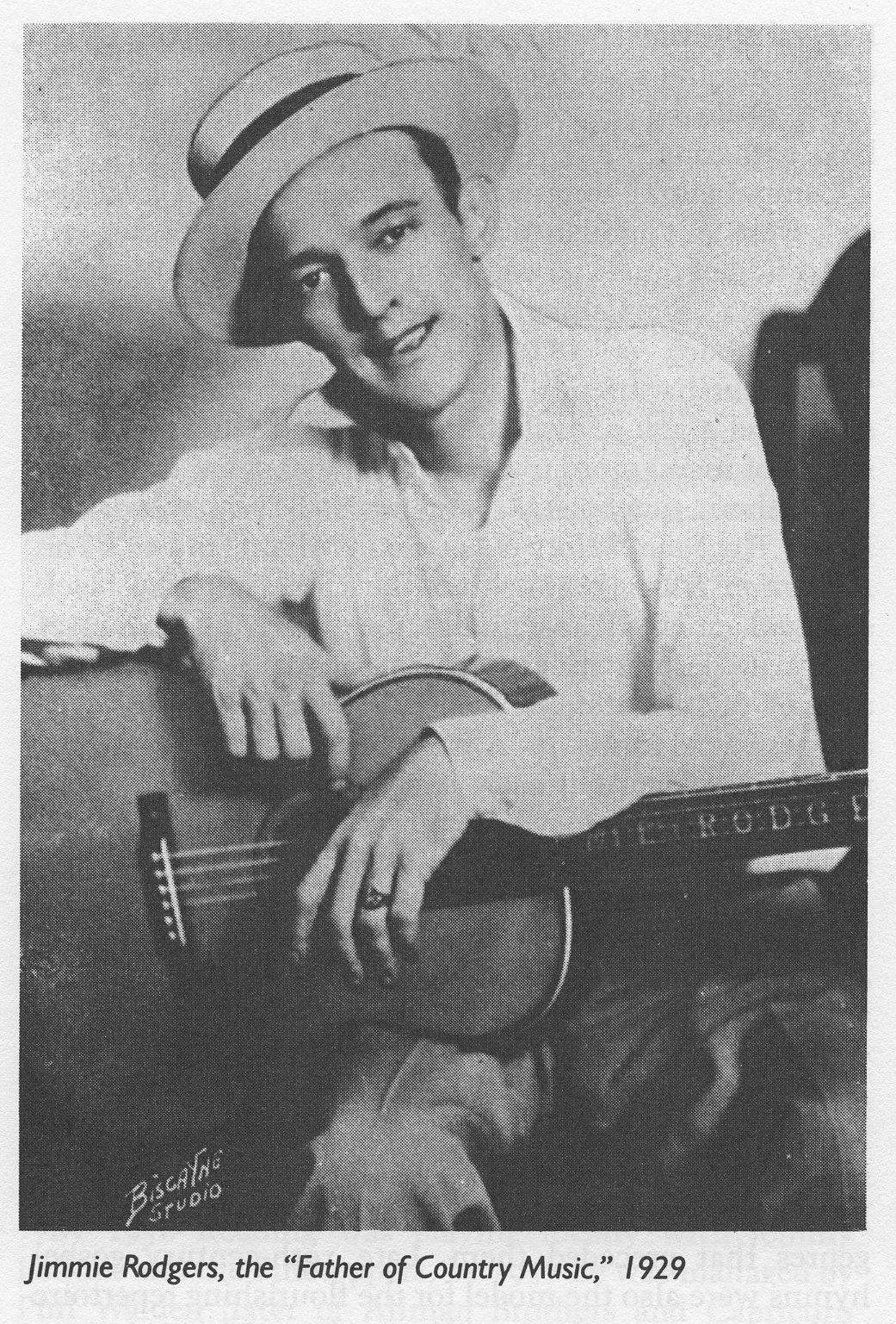 Celebrity 桌布 壁紙 — 一張復古黑白肖像，Jimmie Rodgers 在錄音室環境中微笑著抱著一把原聲吉他。
