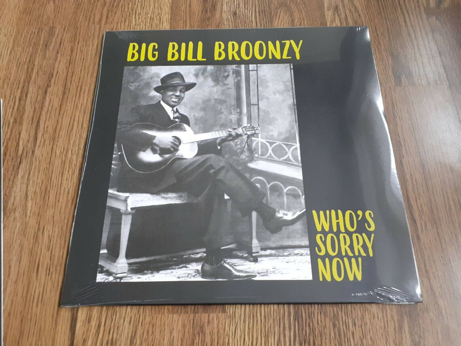poster 桌布 壁紙 — 一張復古黑膠唱片封面，Big Bill Broonzy 微笑著坐在長凳上彈吉他，背景是木地板。