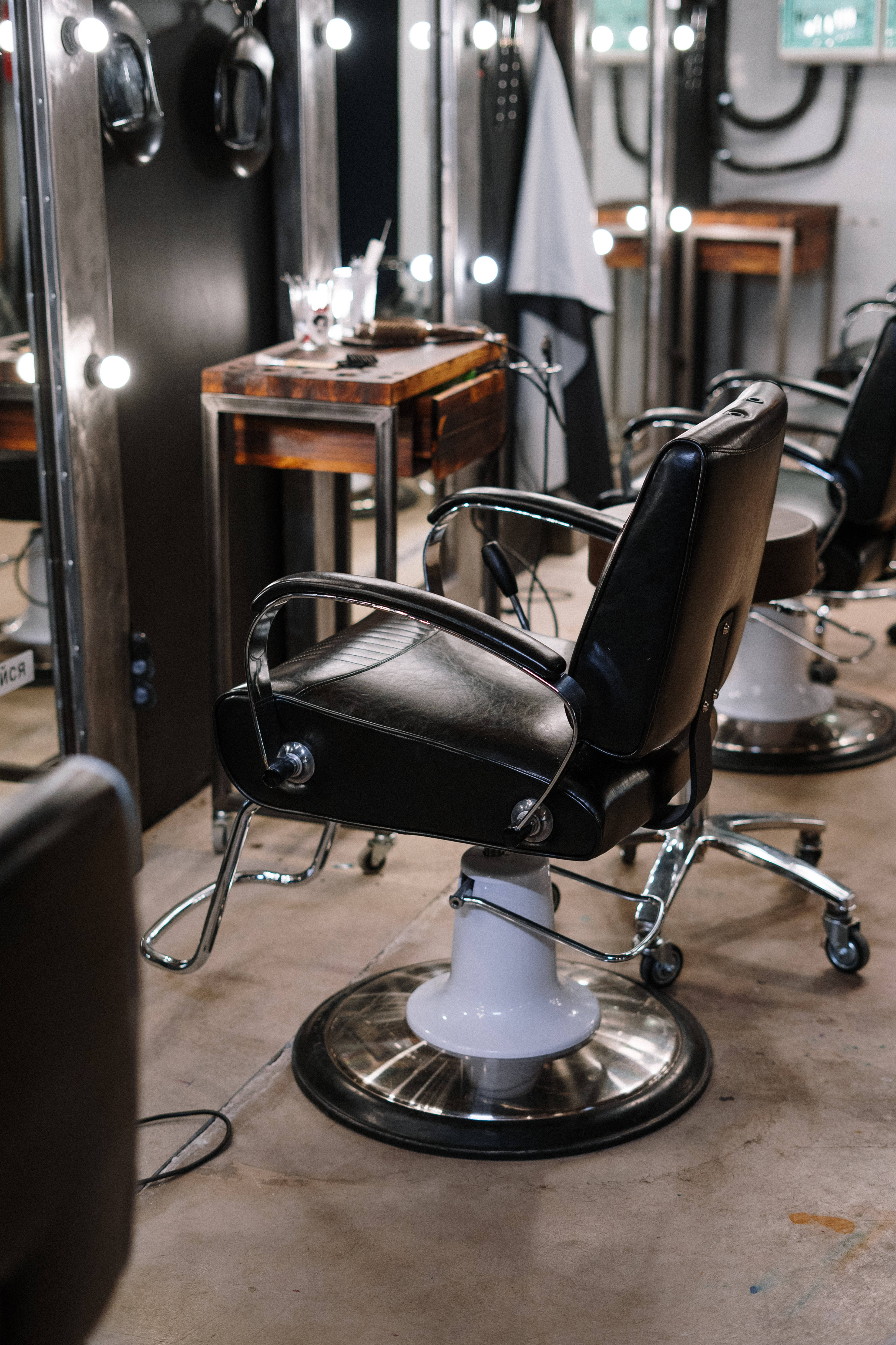 Salon 桌布 壁紙 — 一張復古黑色理髮椅，配以鍍鉻椅腳，置於明亮鏡燈照亮的復古理髮店中。
