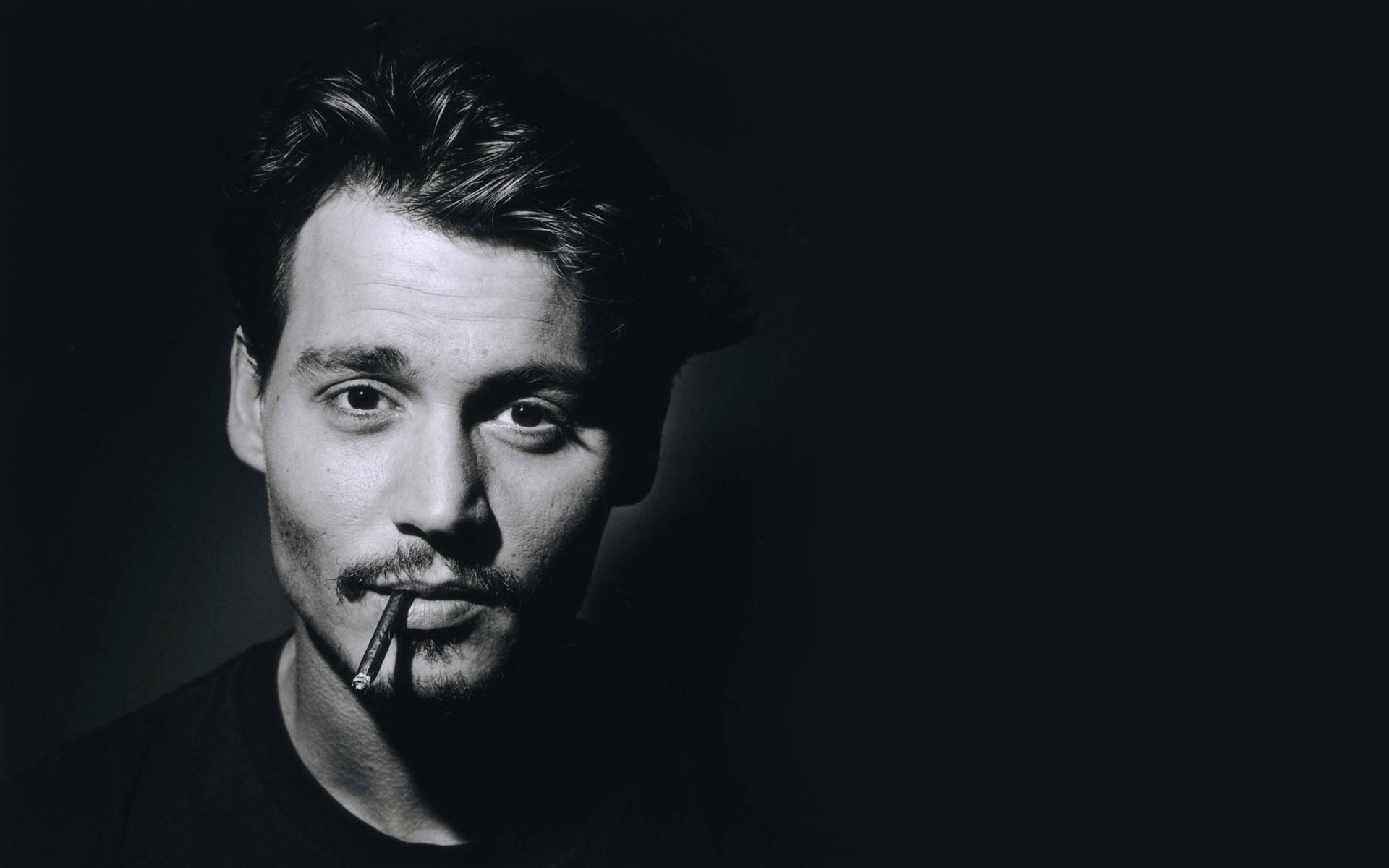 強尼·戴普 桌布 壁紙 — 一張憂鬱的黑白肖像，Johnny Depp 嘴裡叼著香煙，背景陰暗。