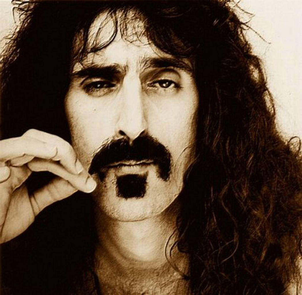 Zappa 桌布 壁紙 — 一張懷舊棕色調的特寫肖像，一名留著長捲髮和獨特八字鬍的男子手持香菸。
