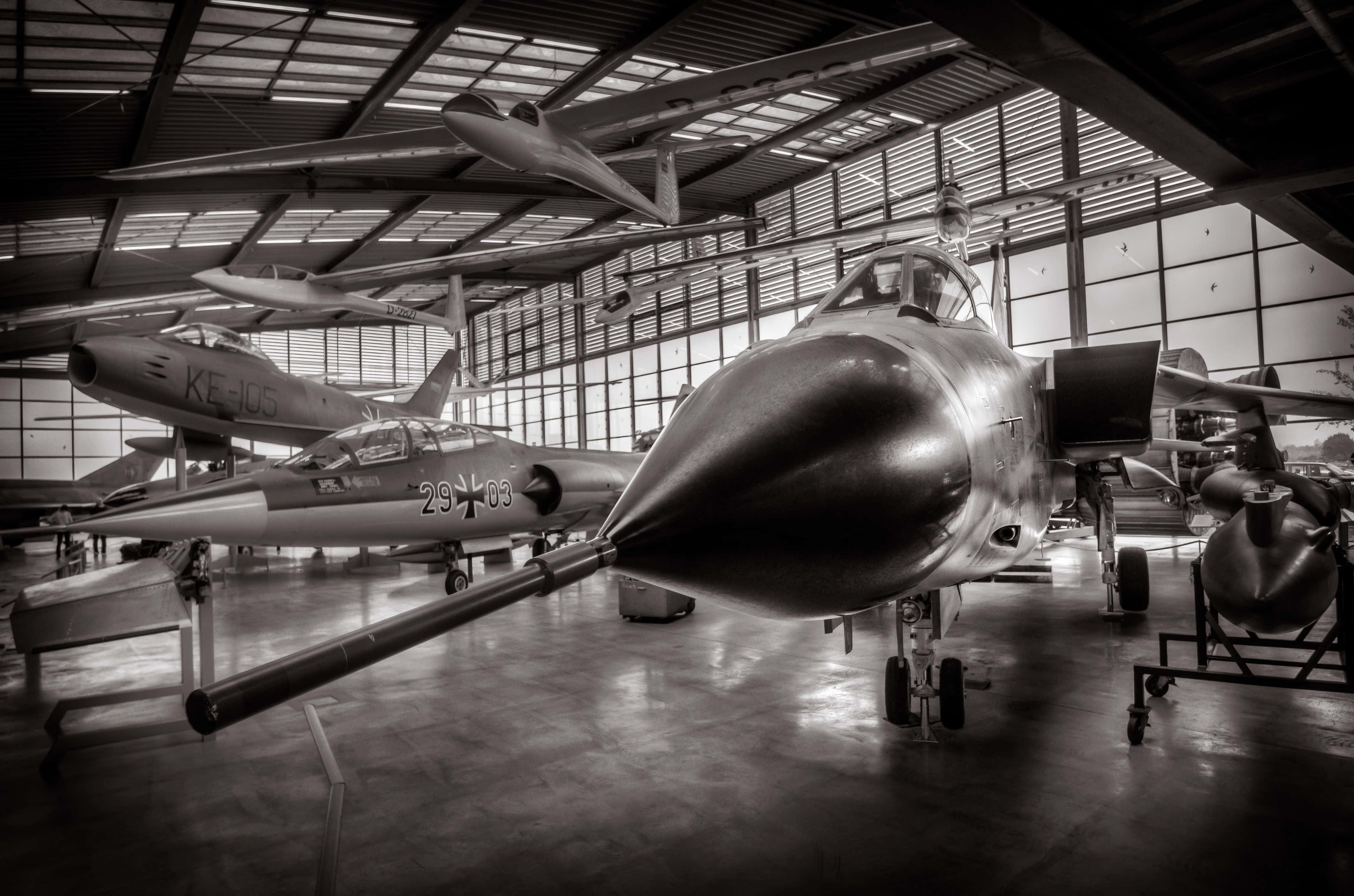 Museums 桌布 壁紙 — 一張戲劇性的黑白照片，展示在寬敞航空博物館機庫內的復古戰鬥機。