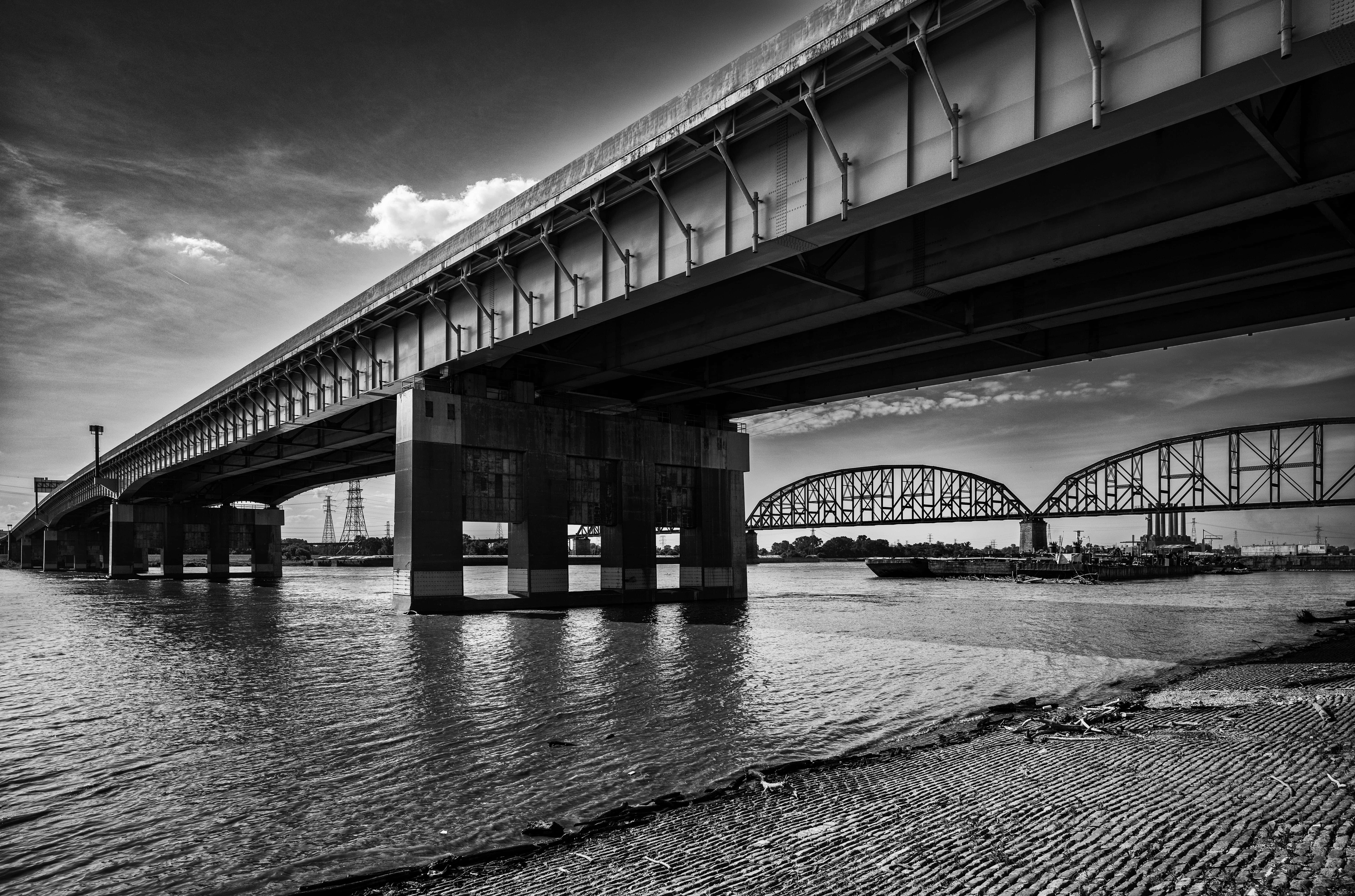 Photography Desktop 桌布 壁紙 — 一張戲劇性的黑白照片，顯示兩座鋼橋在陰天下橫跨寬闊的河流。