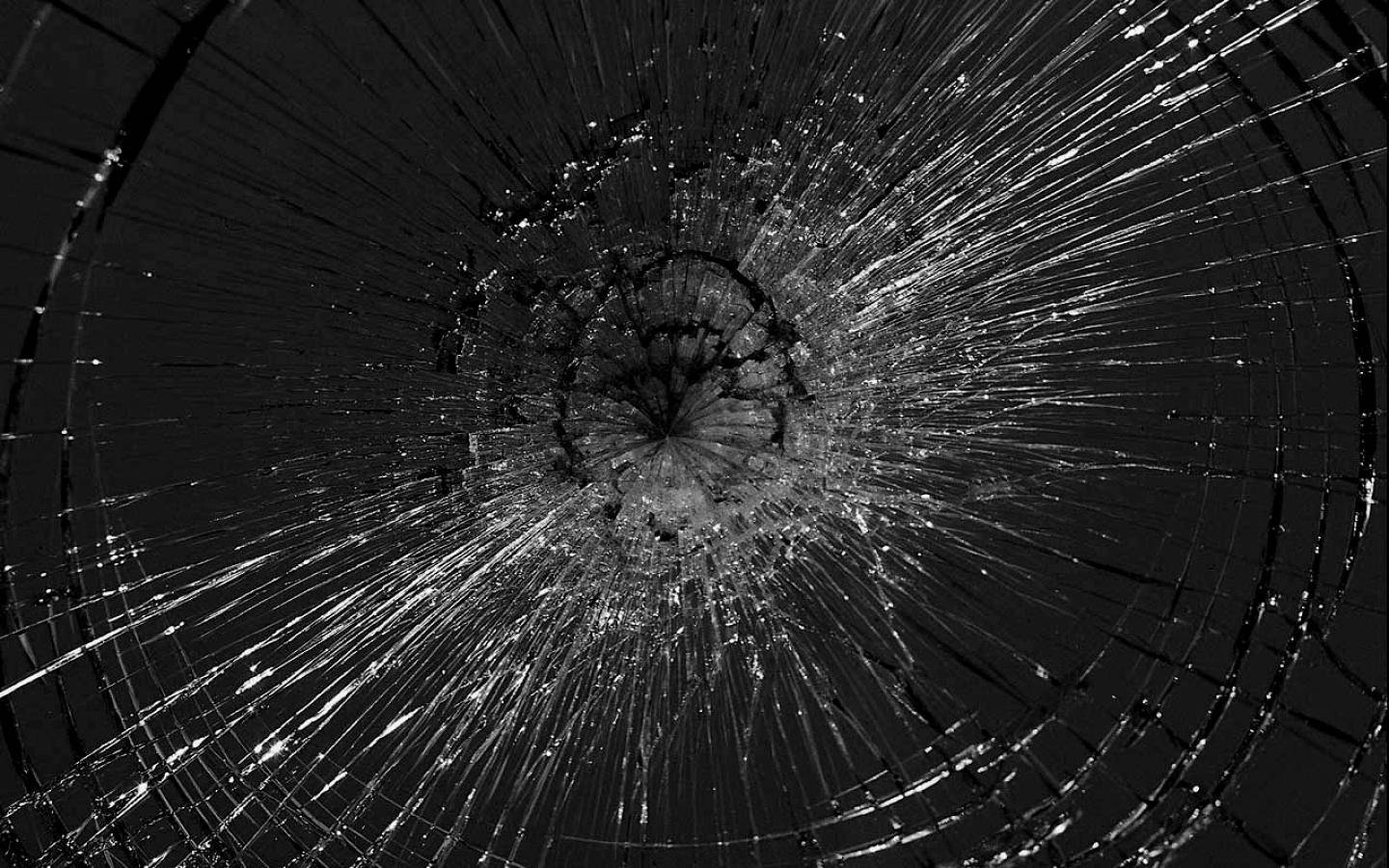 Broken Computer Screen 桌布 壁紙 — 一張戲劇性的黑白特寫，展示從中央撞擊點放射出裂紋的破碎玻璃。