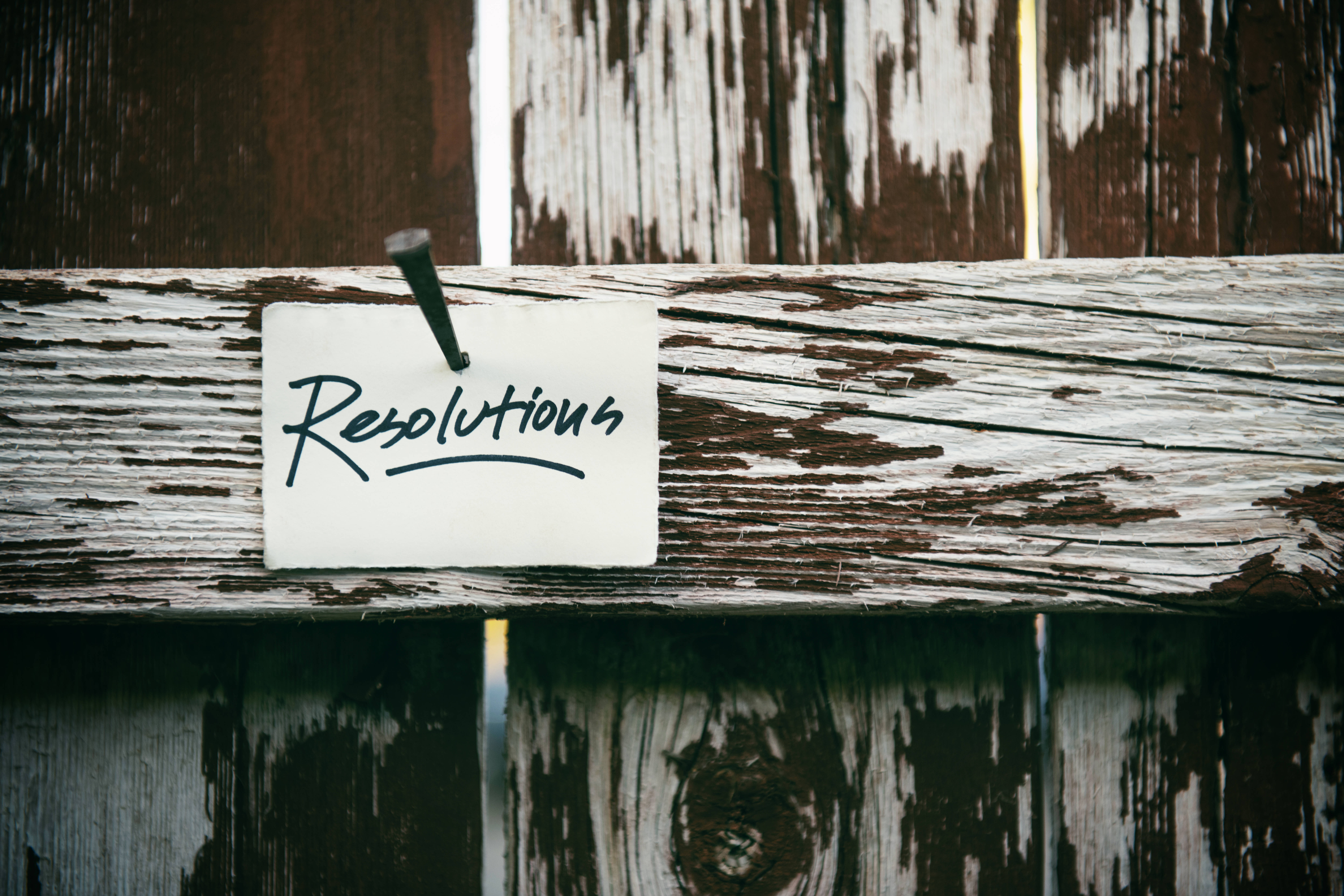 Motivation 桌布 壁紙 — 一張手寫便條，上面寫著「Resolutions」，用圖釘釘在油漆剝落的風化木柵欄上。