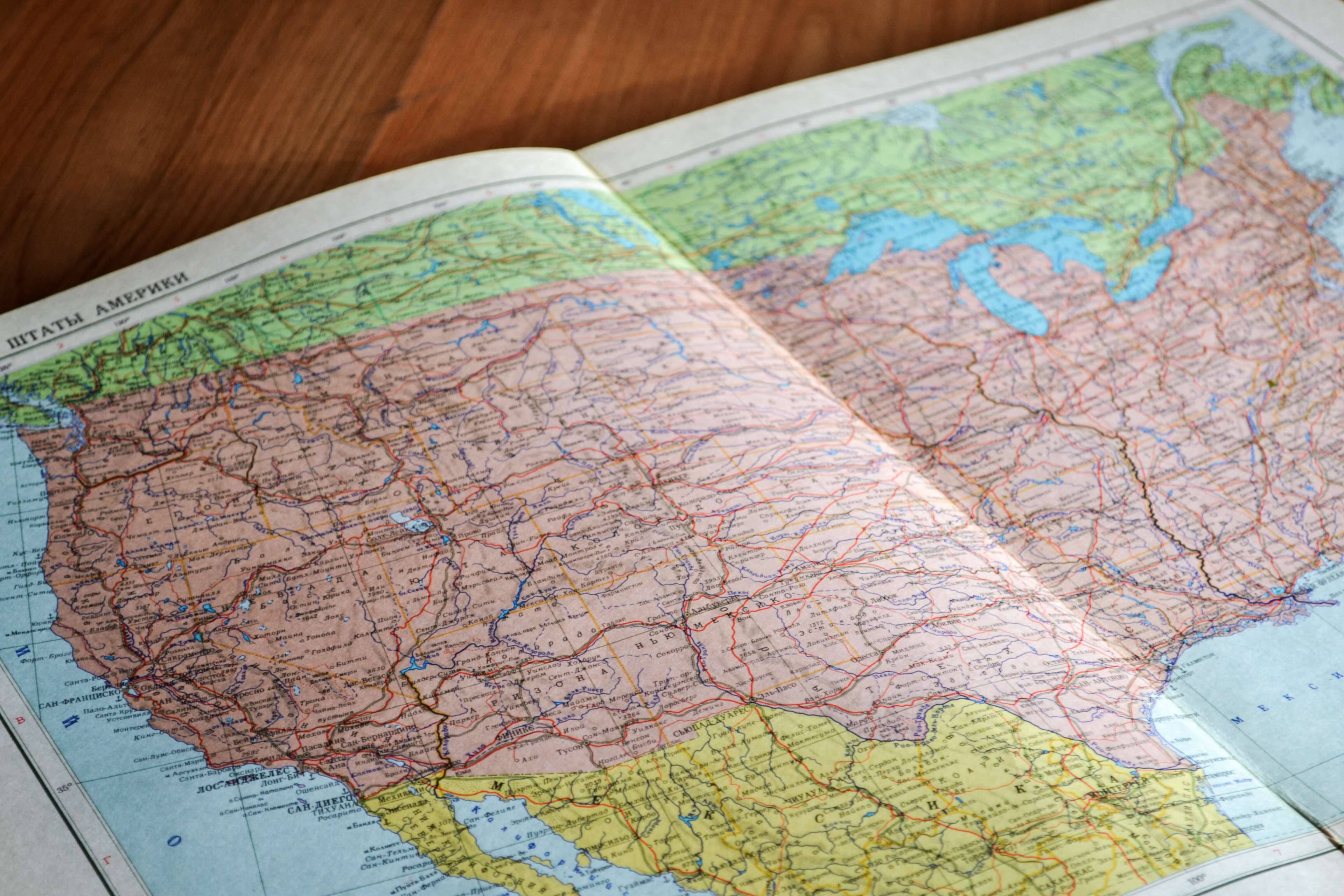 United States Map 桌布 壁紙 — 一張打開的北美復古地圖放在木桌上，顯示詳細的道路和地理特徵。