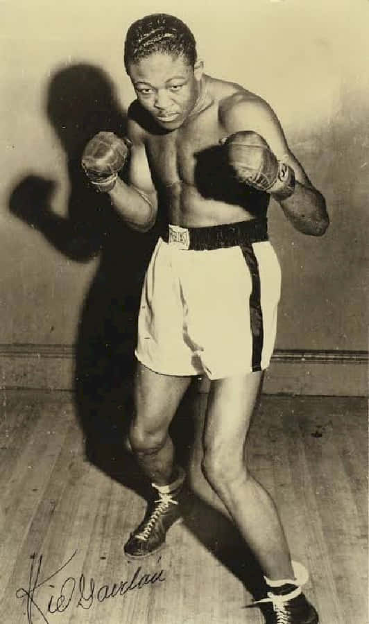 Boxing 桌布 壁紙 — 一張拳擊手基德·加維蘭在素牆前擺出戰鬥姿勢、帶有戲劇性陰影的復古黑白照片。