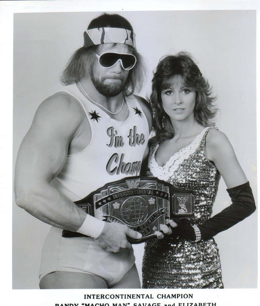 WWE 桌布 壁紙 — 一張摔角手 Randy Savage 手持冠軍腰帶、妻子 Elizabeth 在旁擺姿勢的黑白照片。