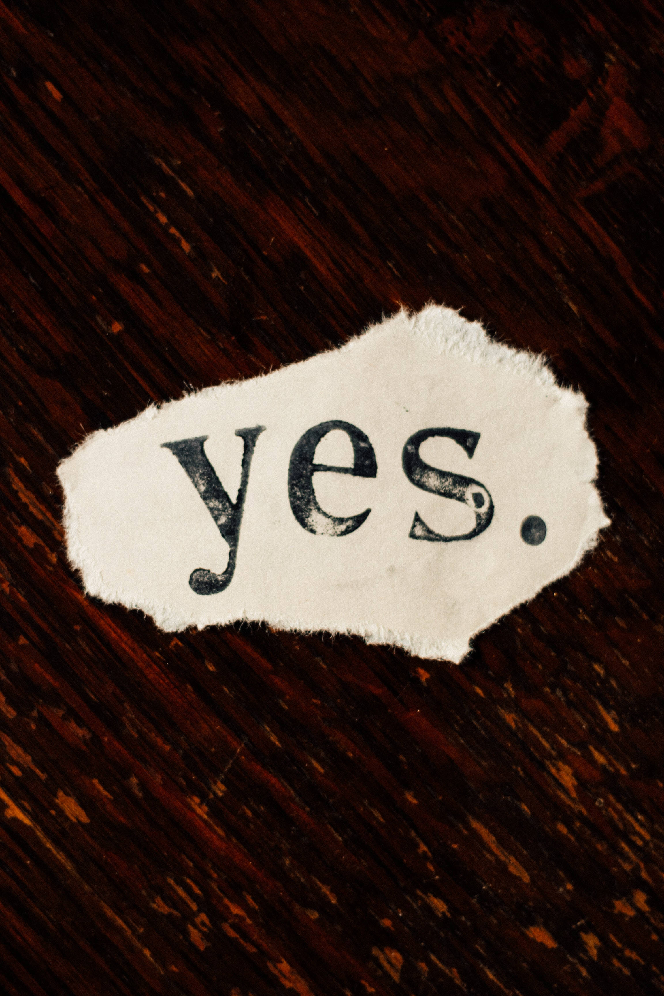 激勵 桌布 壁紙 — 一張撕破的白紙，上面用復古黑色墨水寫著「yes.」，放在深色木紋表面上。