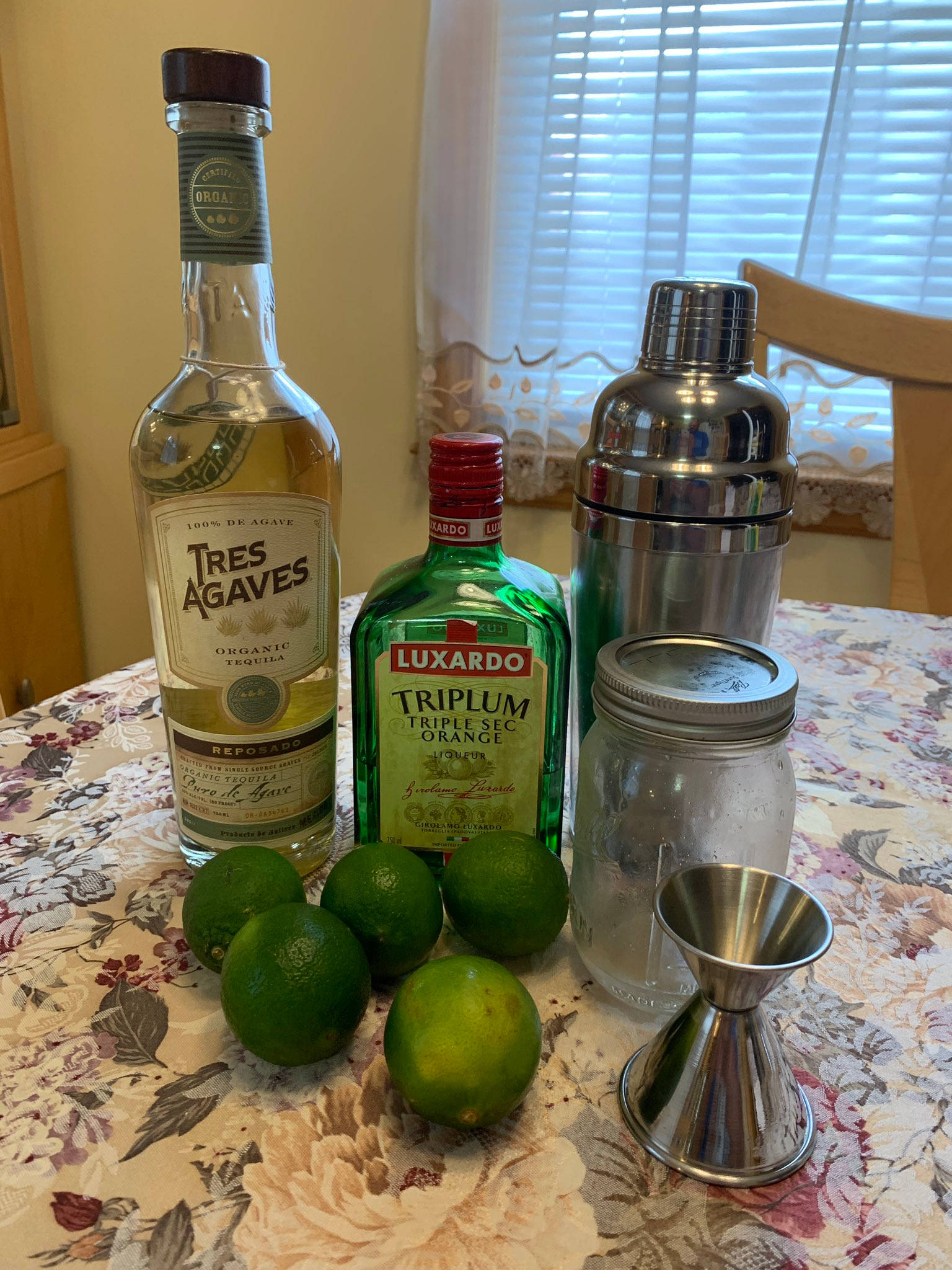 bottle 桌布 壁紙 — 一張擺放著龍舌蘭酒、橙皮甜酒、萊姆和雞尾酒工具的桌子，準備好調製飲品。