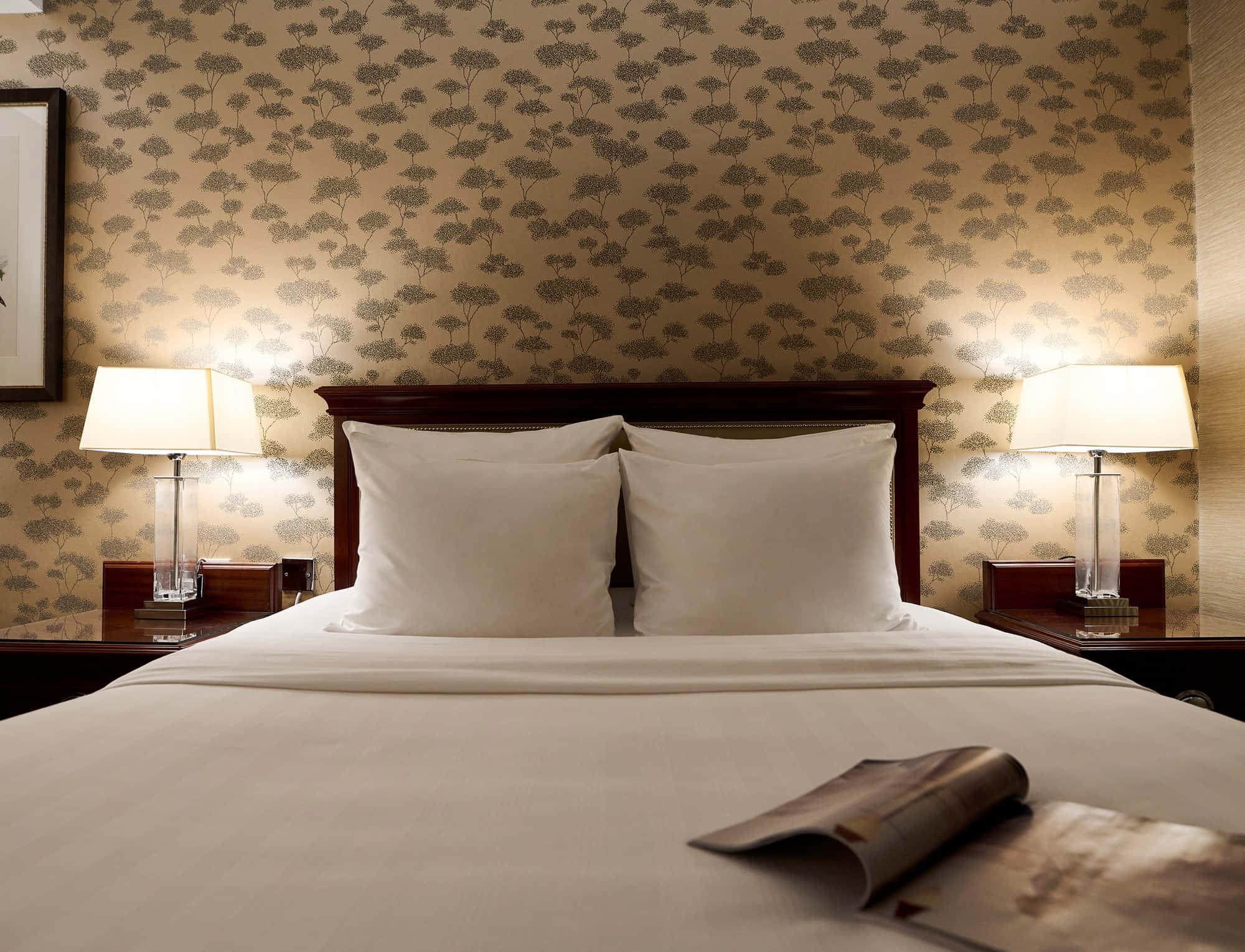Bedroom 桌布 壁紙 — 一張整齊整理的酒店床，配有白色床單和兩盞燈，在圖案壁紙背景下溫暖地發光。