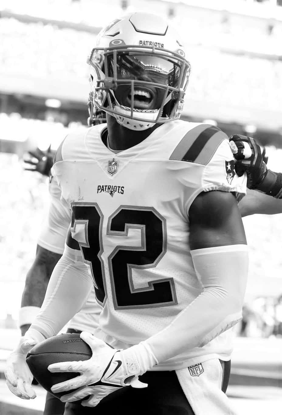 Devin Mccourty 桌布 壁紙 — 一張新英格蘭愛國者隊美式足球員32號在球場上拿著足球慶祝的黑白照片。
