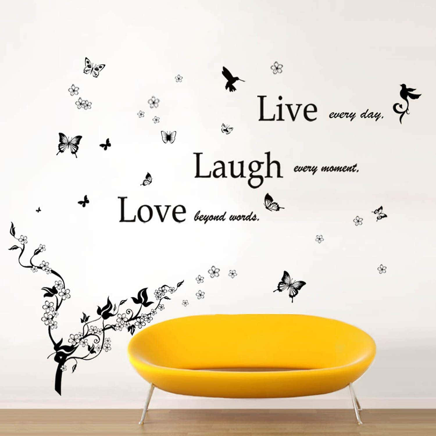 Live Laugh Love 桌布 壁紙 — 一張明亮的黃色現代沙發放在白色牆壁下，牆上裝飾著黑色蝴蝶花卉貼紙和勵志語句。