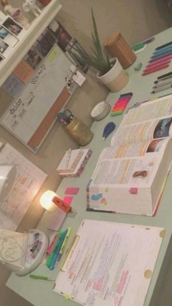 一張書桌，上面有書本、筆和蠟燭 壁紙