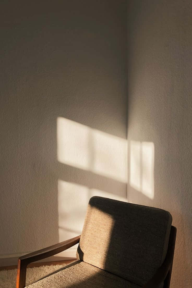 Minimalist Photography 桌布 壁紙 — 一張木製扶手椅放在角落，沐浴在柔和陽光下，在紋理牆壁上投射出長方形陰影。