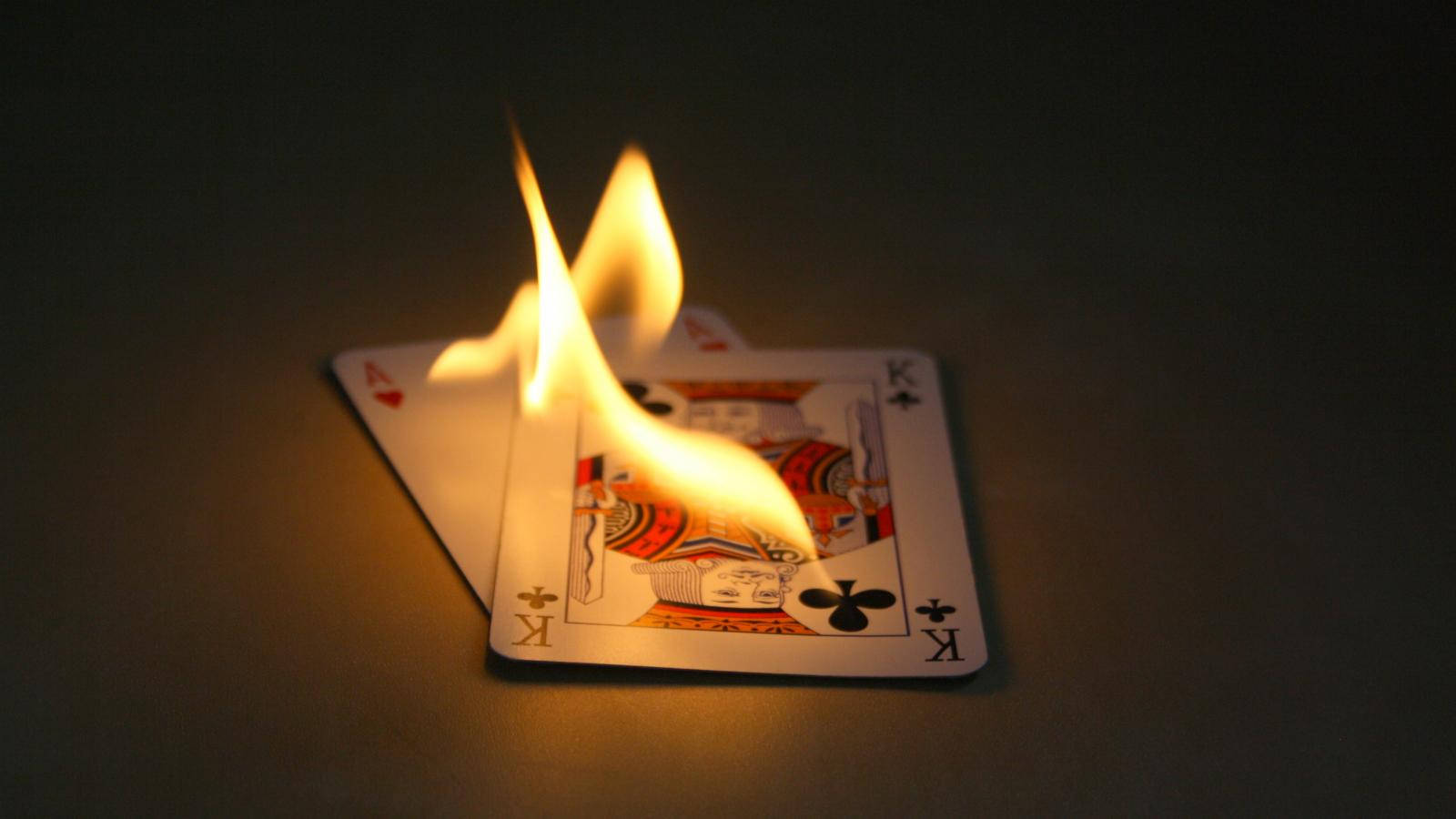 Casino 桌布 壁紙 — 一張梅花K撲克牌在黑暗背景下燃燒著明亮的橙色火焰。