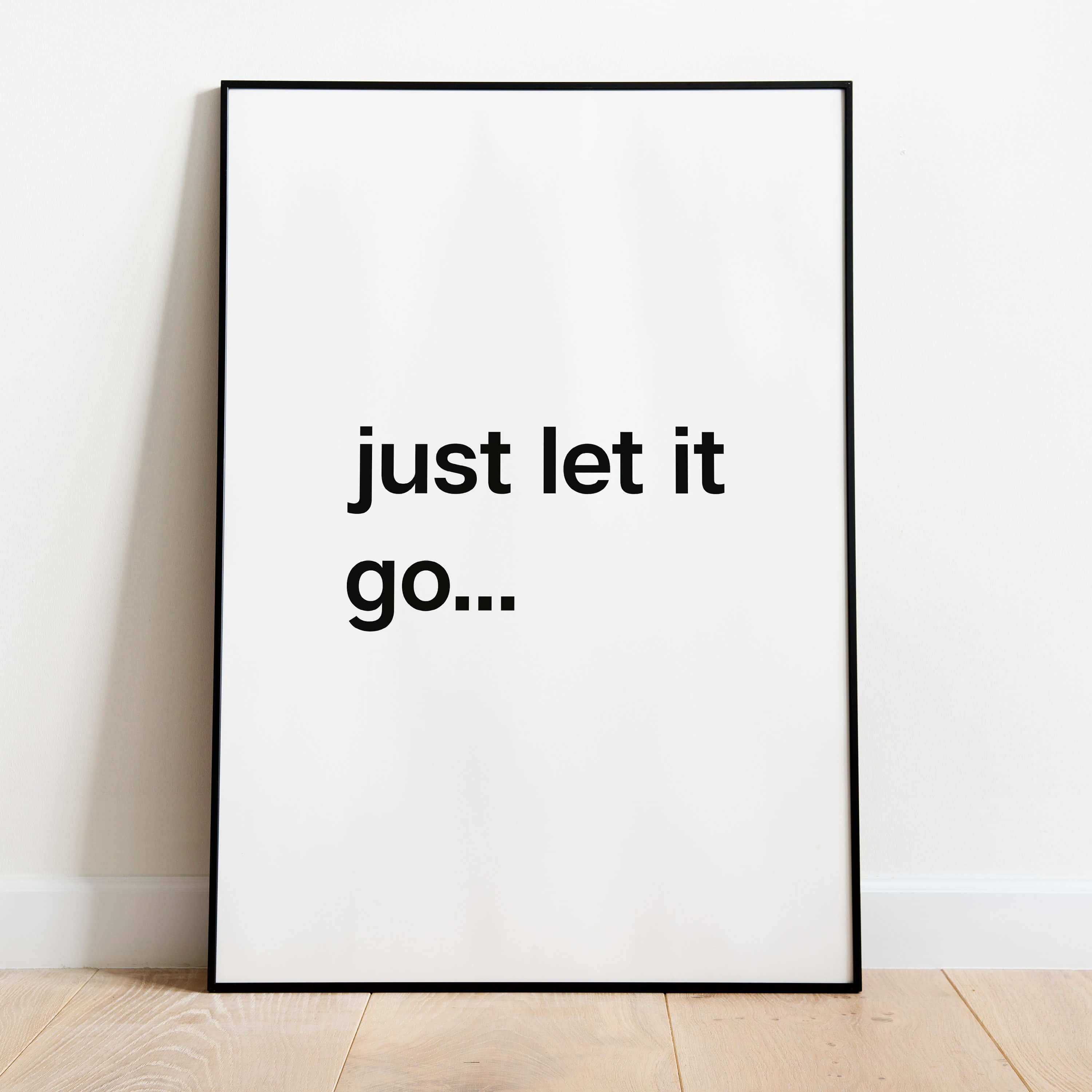let it go 桌布 壁紙 — 一張極簡風格的黑色邊框海報，上面寫著「just let it go...」，靠在一面白牆上，下方是淺色木地板。