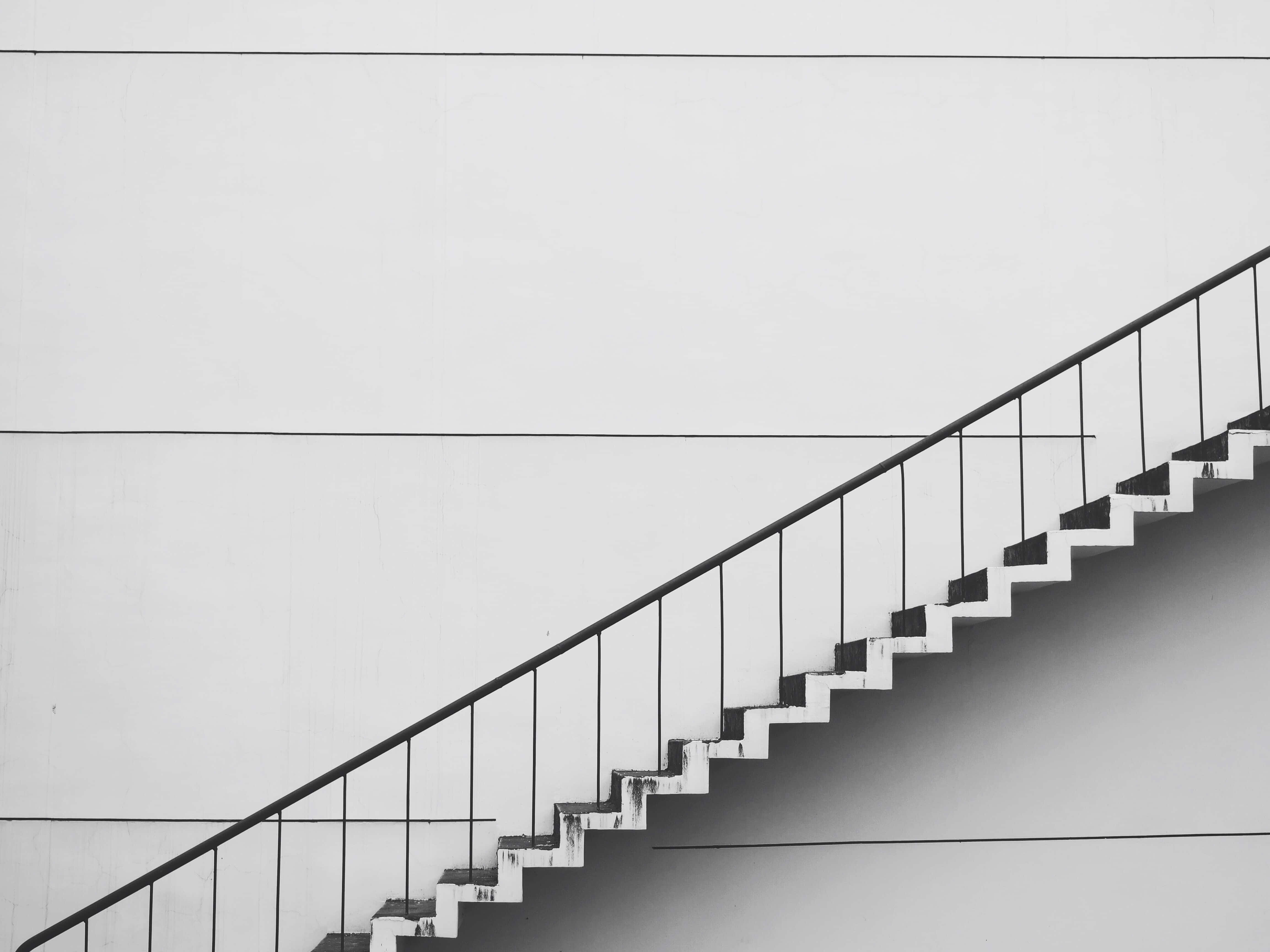 stairs 桌布 壁紙 — 一張極簡黑白照片，呈現幾何樓梯沿對角線向上延伸至素色牆壁。