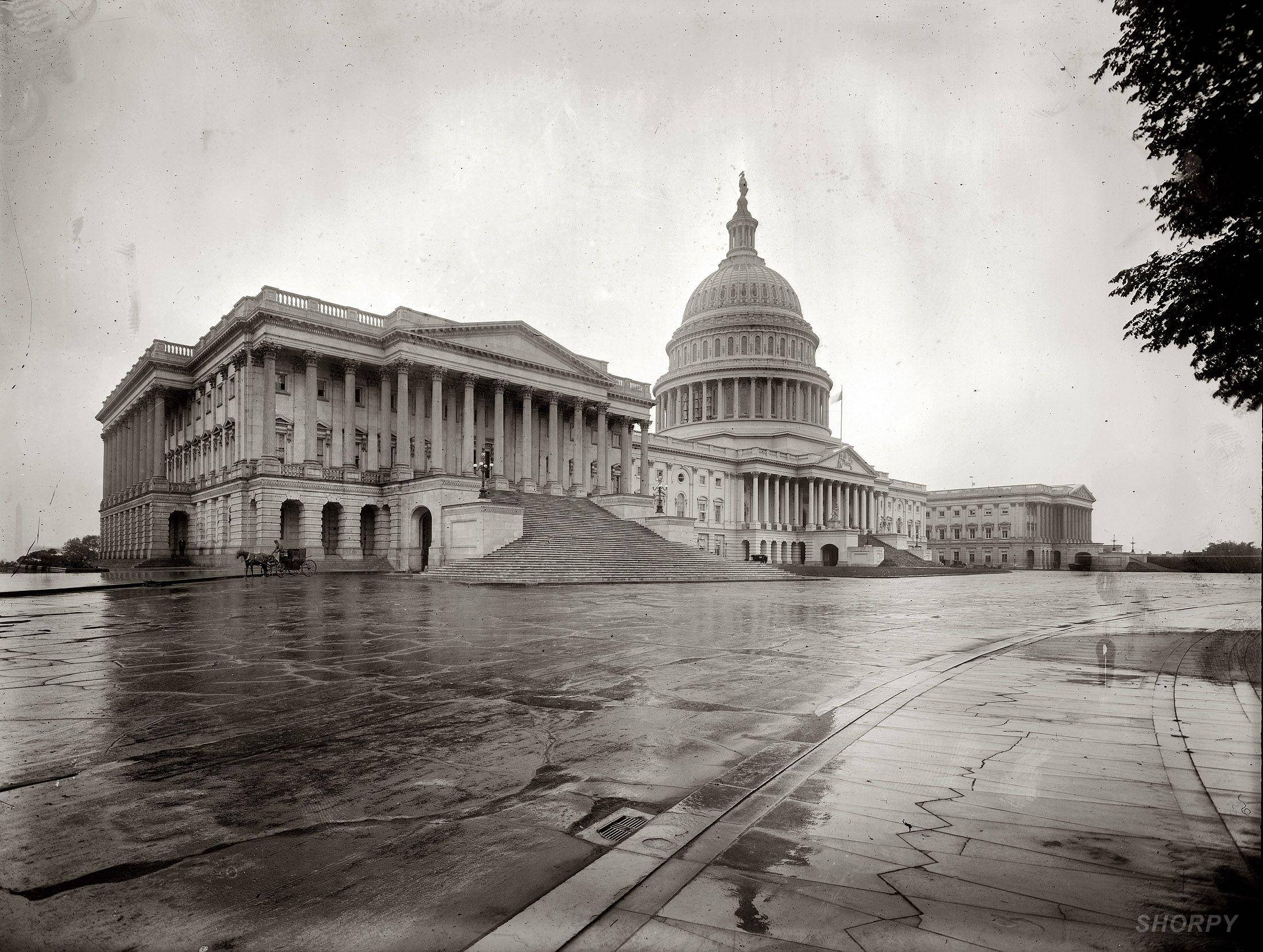 America 桌布 壁紙 — 一張歷史性的黑白照片，拍攝美國國會大廈在雨天中，濕漉漉的路面反射出其宏偉的新古典主義建築風格。