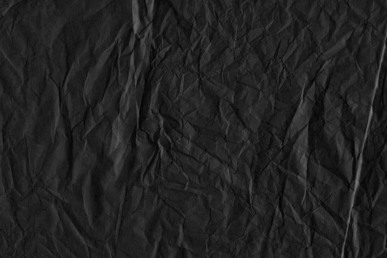Black Paper Texture 桌布 壁紙 — 一張深皺黑色紙張的特寫，微妙的陰影突顯其紋理表面。