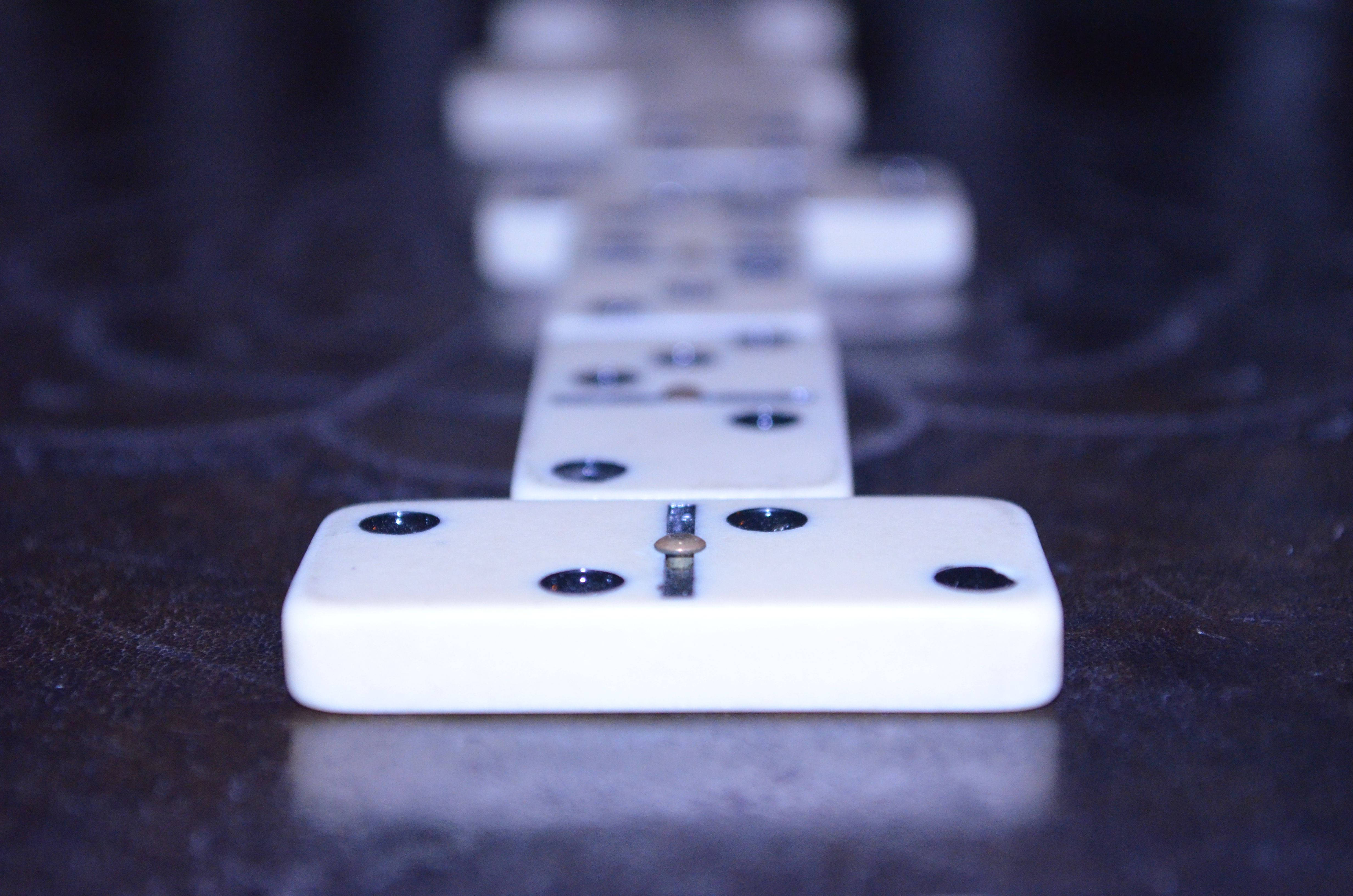 Domino 桌布 壁紙 — 一張淺景深照片，白色骨牌排列在深色紋理表面上，前景的一塊插有金屬針。