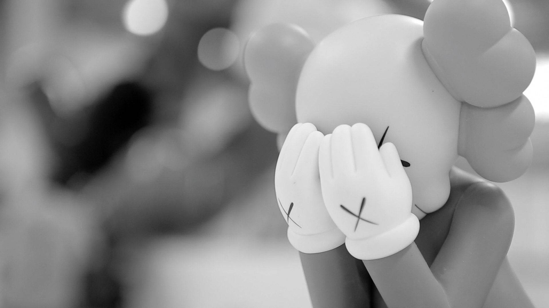 kaws 4K 桌布 壁紙 — 一張淺景深的黑白照片，展示KAWS公仔用手遮住臉部。