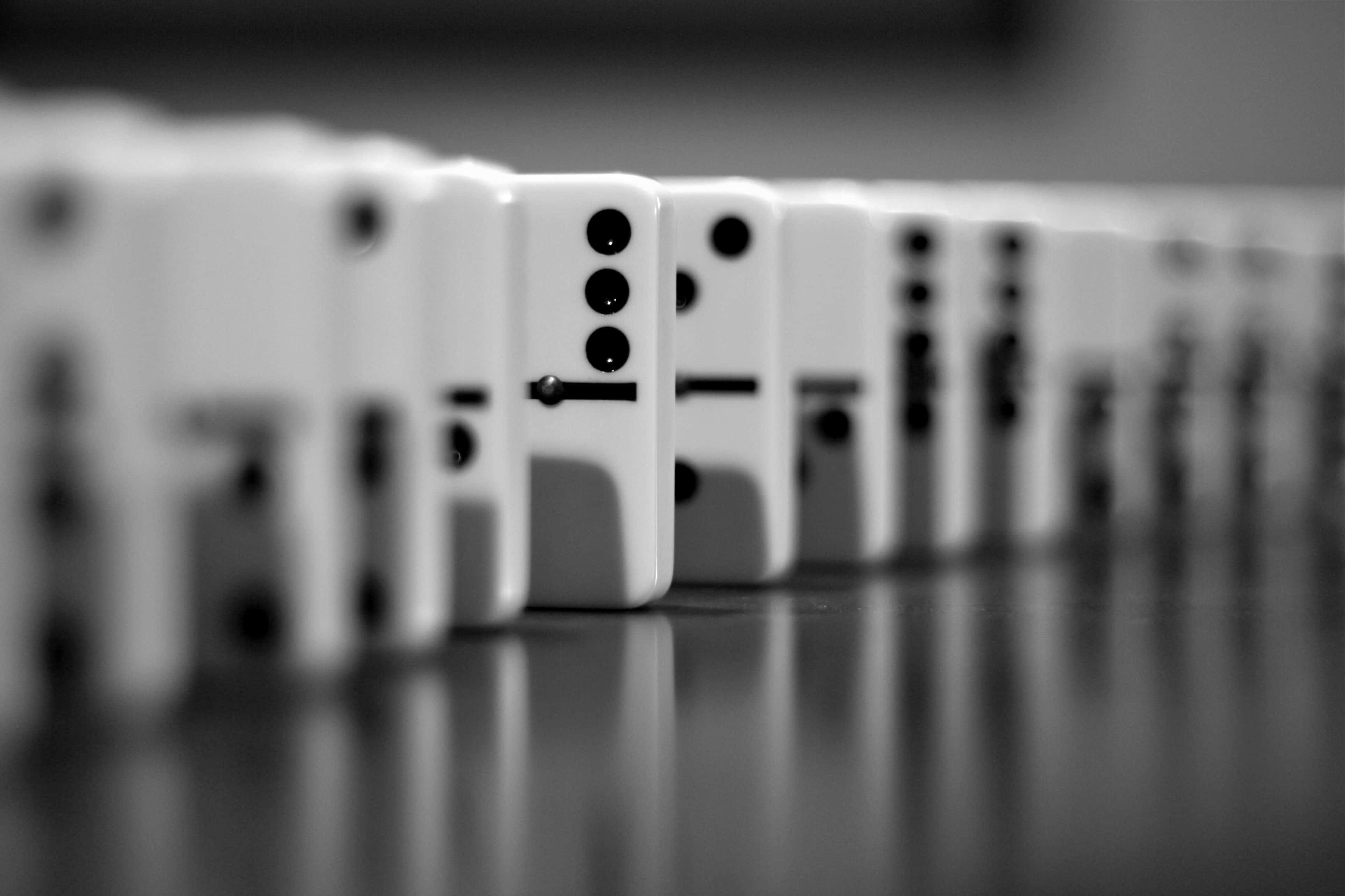 Domino 桌布 壁紙 — 一張淺景深黑白照片，展示排列在反光表面上的一排骨牌。