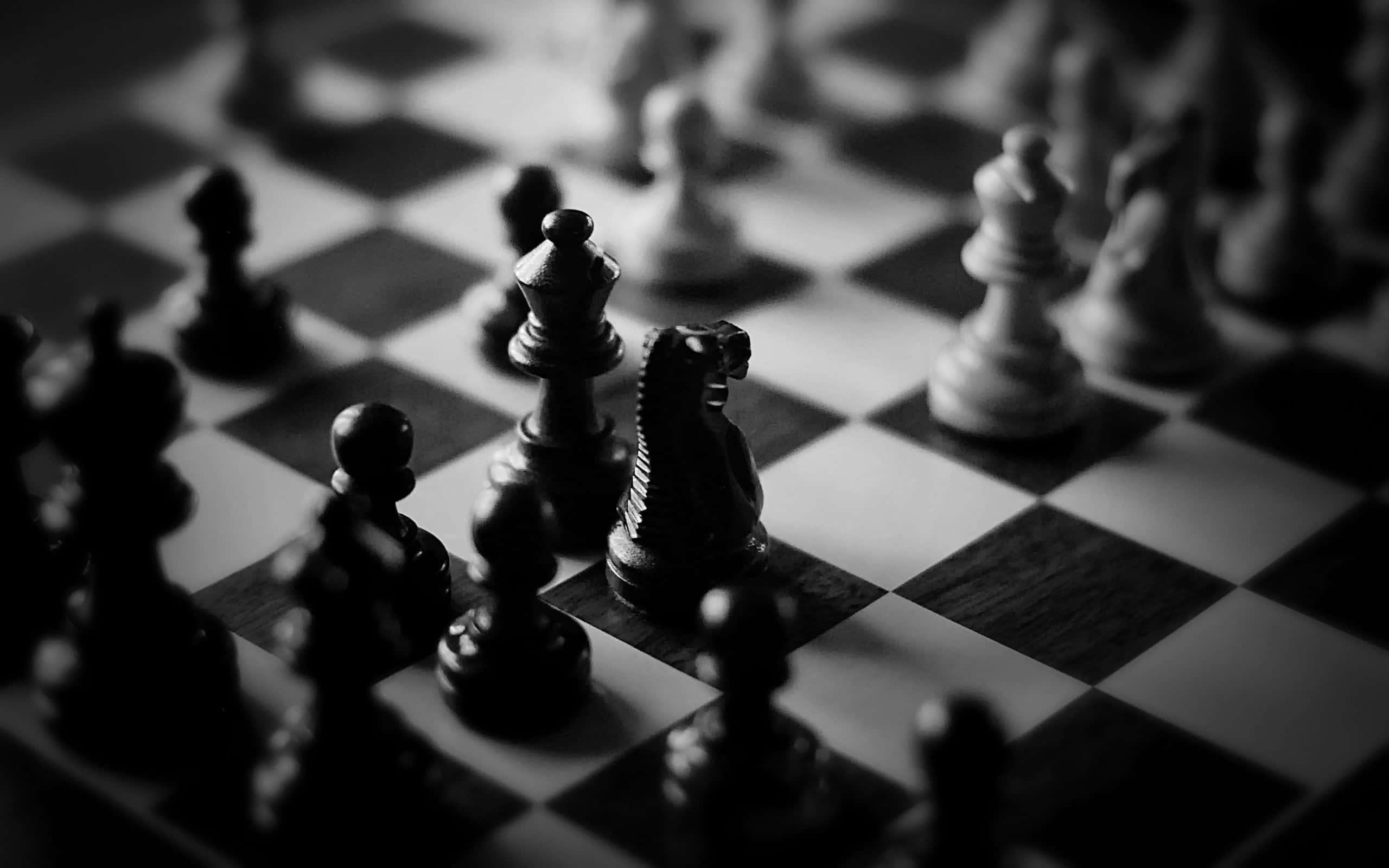 Black And White Chess 桌布 壁紙 — 一張淺景深黑白照片，顯示木製棋盤上的西洋棋棋子，騎士處於焦點。