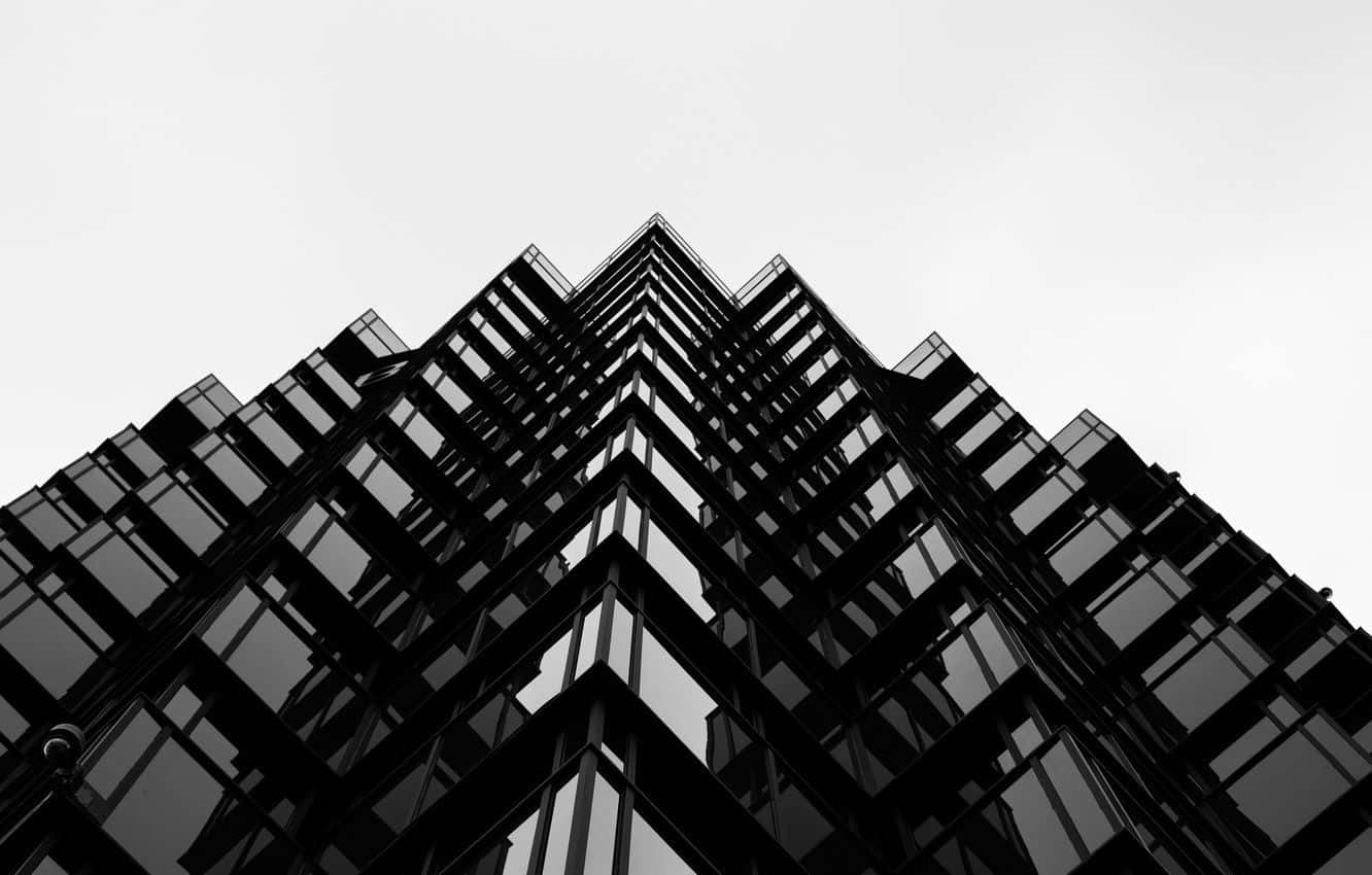 Black And White Architecture 桌布 壁紙 — 一張清晰的黑白低角度照片，現代玻璃摩天大樓刺穿蒼白的天空。