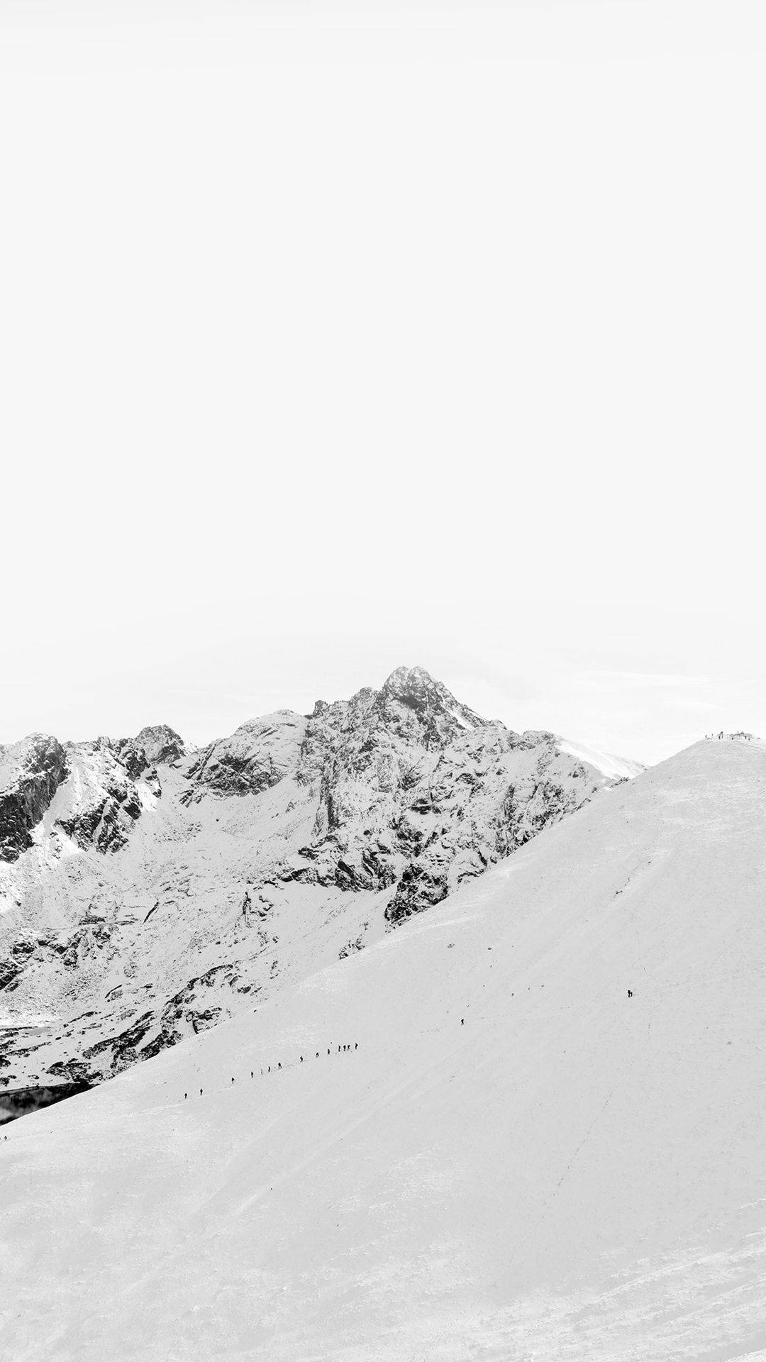 山景 桌布 壁紙 — 一張清晰的黑白照片，拍攝了白雪覆蓋的山峰，細小的登山者在陰天中攀登陡峭的山坡。