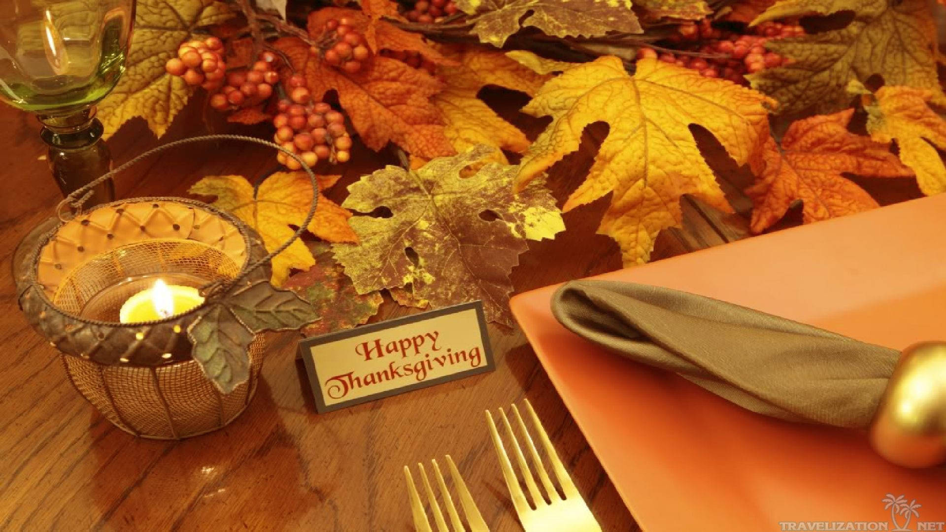 Thanksgiving Day 桌布 壁紙 — 一張溫暖照明的感恩節餐桌，擺放著秋葉、漿果、蠟燭和金色餐具。