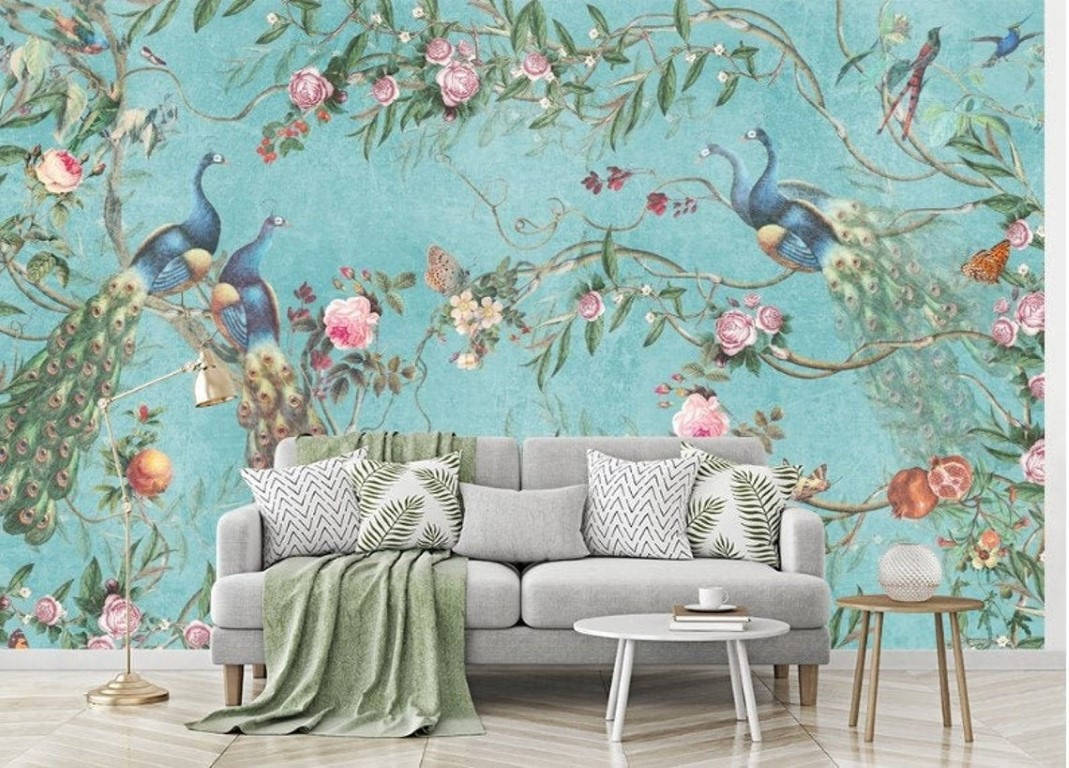 Chinoiserie 桌布 壁紙 — 一張灰色沙發放在充滿活力的藍綠色壁紙前，壁紙上飾有孔雀、粉紅玫瑰和翩翩飛舞的蝴蝶。