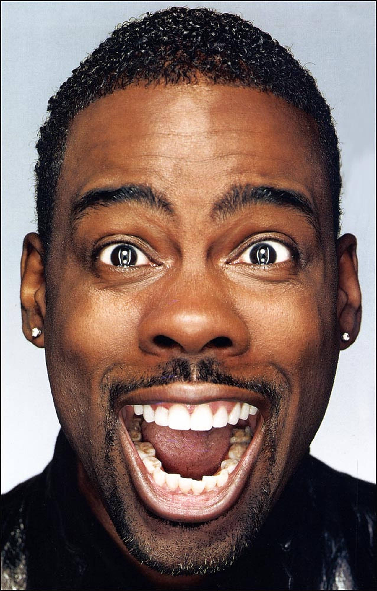 Chris Rock 桌布 壁紙 — 一張特寫照片，一名男子睜大眼睛、張開嘴巴，在純色背景前大笑或大喊。