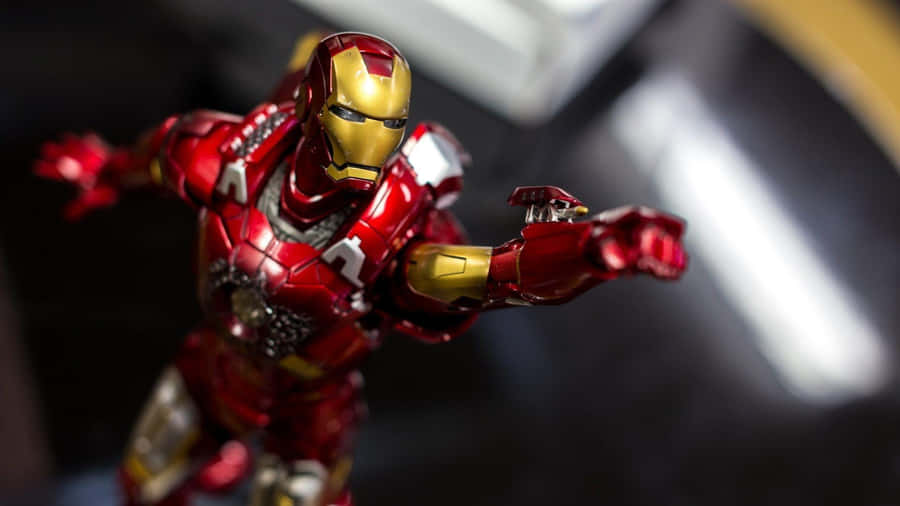 Iron Man Action Figures 桌布 壁紙 — 一張特寫照片，展示了一個細節豐富的紅色和金色鋼鐵人動作人偶，在模糊的深色背景前動態擺姿勢。