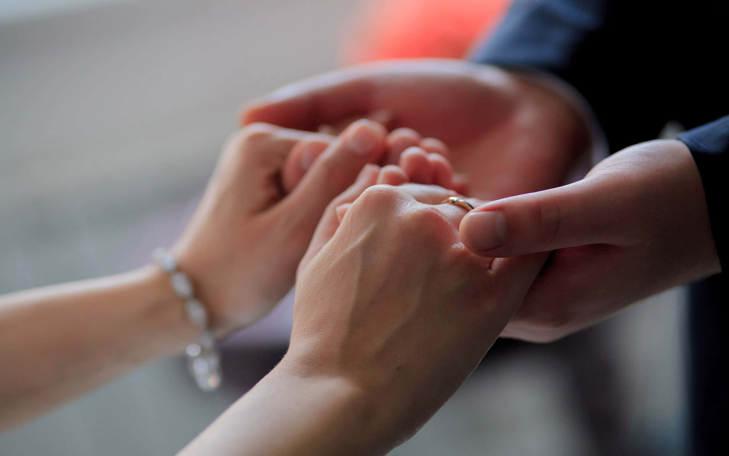 couple love 桌布 壁紙 — 一張特寫照片，雙手輕輕地將金色結婚戒指戴在手指上，背景柔和模糊。