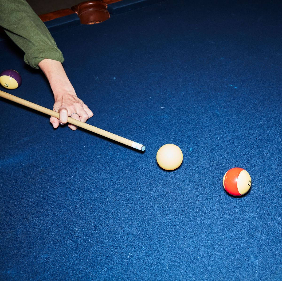 balls 桌布 壁紙 — 一張特寫照片，顯示一個人的手拿著撞球桿瞄準深藍色絨布撞球桌上的一個黃色球。