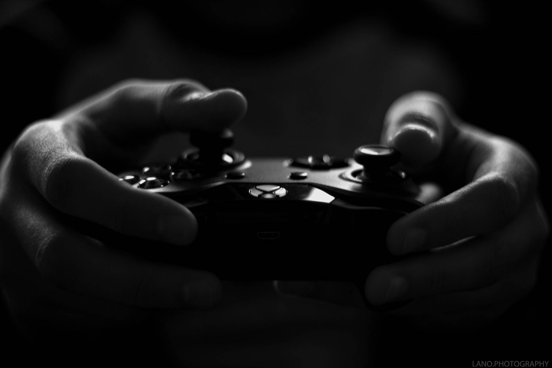 PlayStation 桌布 壁紙 — 一張特寫黑白照片，顯示雙手在深色背景下緊握遊戲控制器。