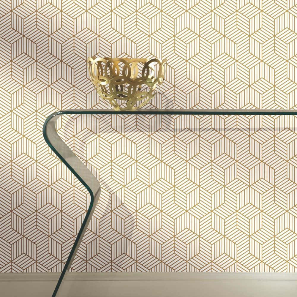 Interior Design 桌布 壁紙 — 一張玻璃玄關桌，上面放著一個金色裝飾碗，靠在一面覆蓋著米色和金色幾何壁紙的牆上。