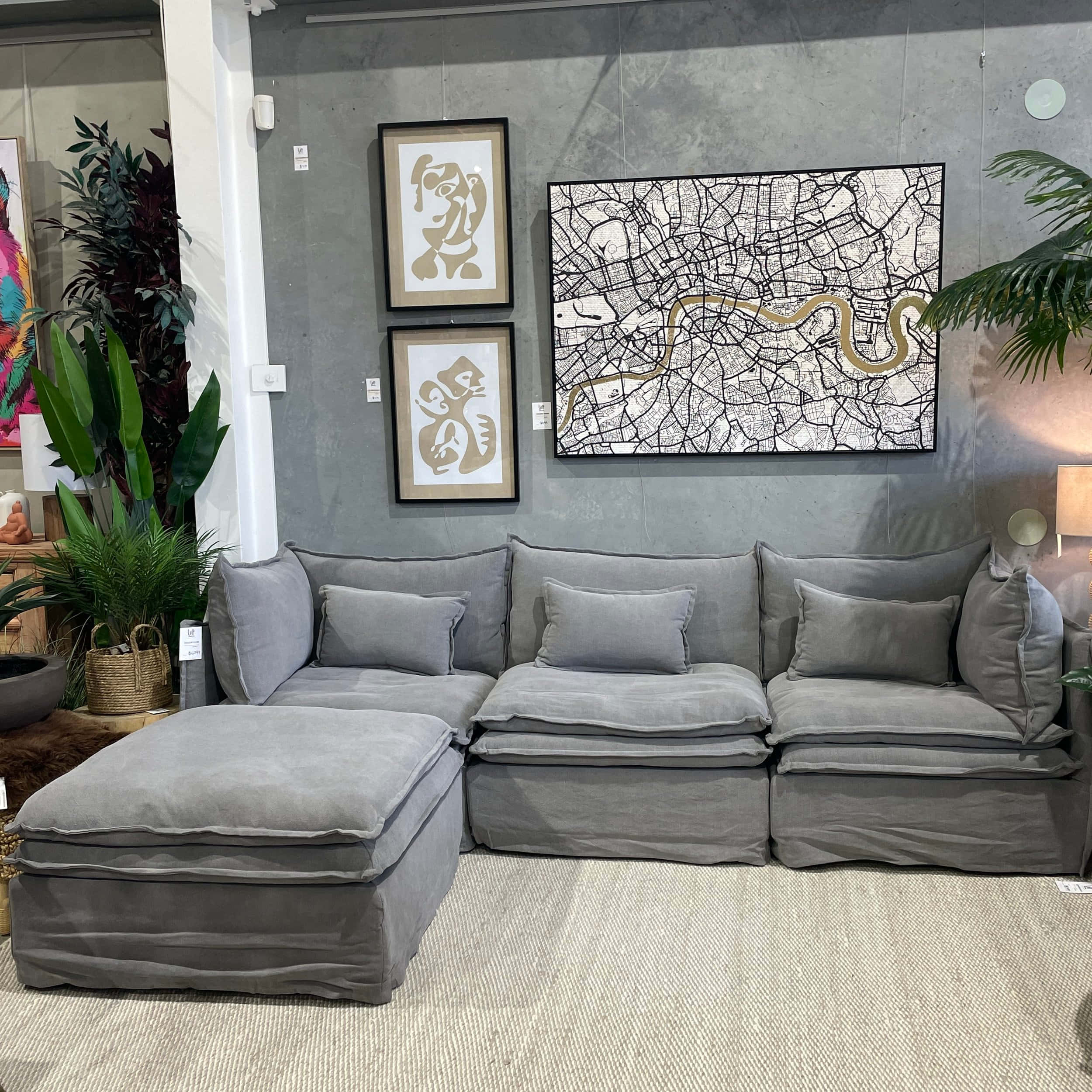 Living Room 桌布 壁紙 — 一張現代灰色組合沙發，配有柔軟靠墊，放置在簡約風格的客廳中，裝飾著抽象藝術和茂盛的綠色植物。