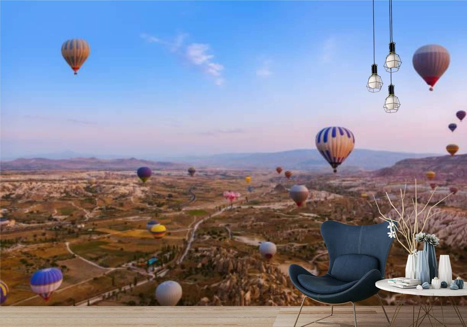 Cappadocia 桌布 壁紙 — 一張現代藍色椅子放在一幅日落時分熱氣球飄浮在峽谷上空的壁畫前。