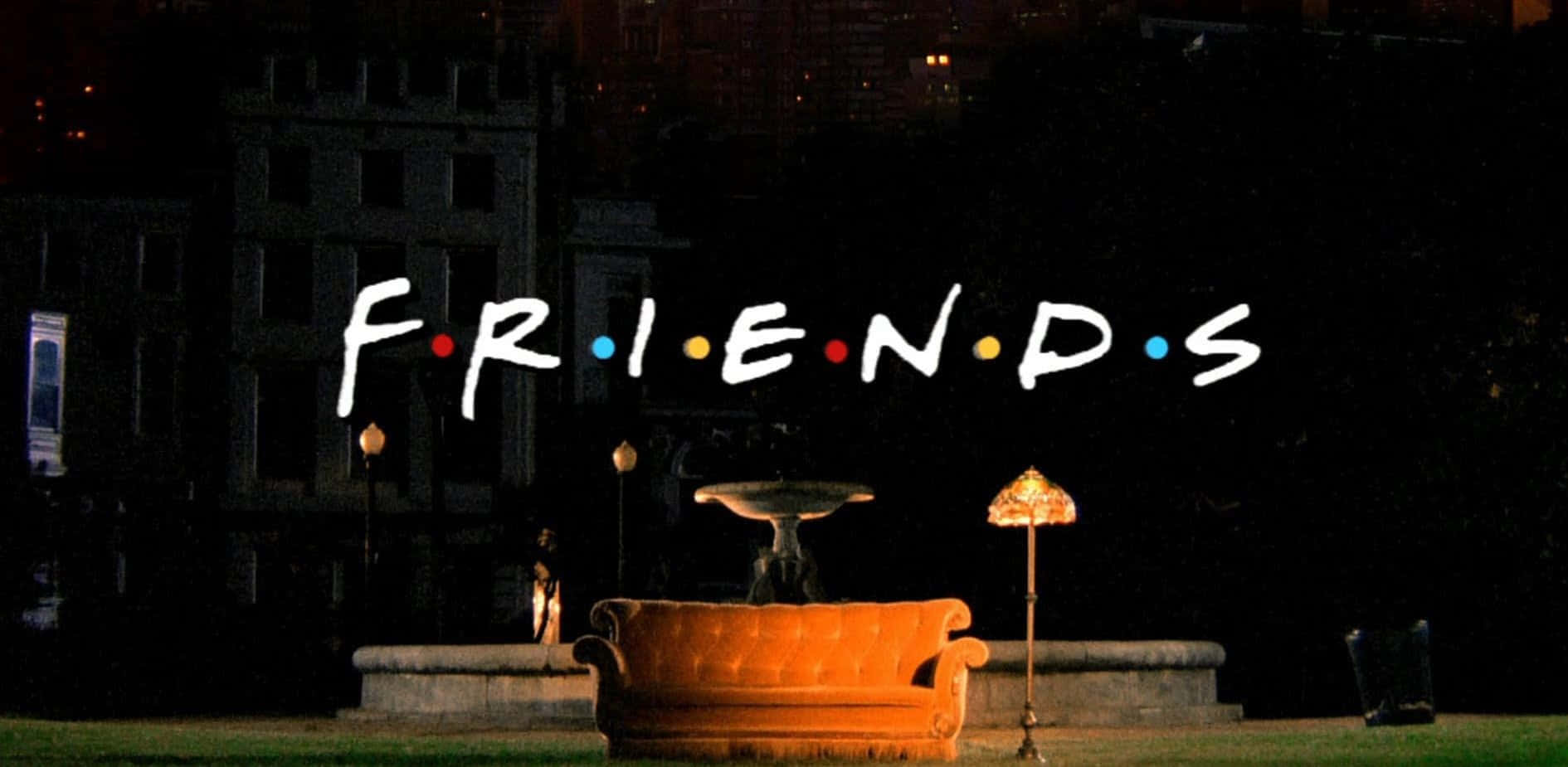 Friendship 桌布 壁紙 — 一張發光的橙色沙發在夜晚的黑暗公園中，'FRIENDS' 標誌漂浮在其上方，背景是城市天際線。